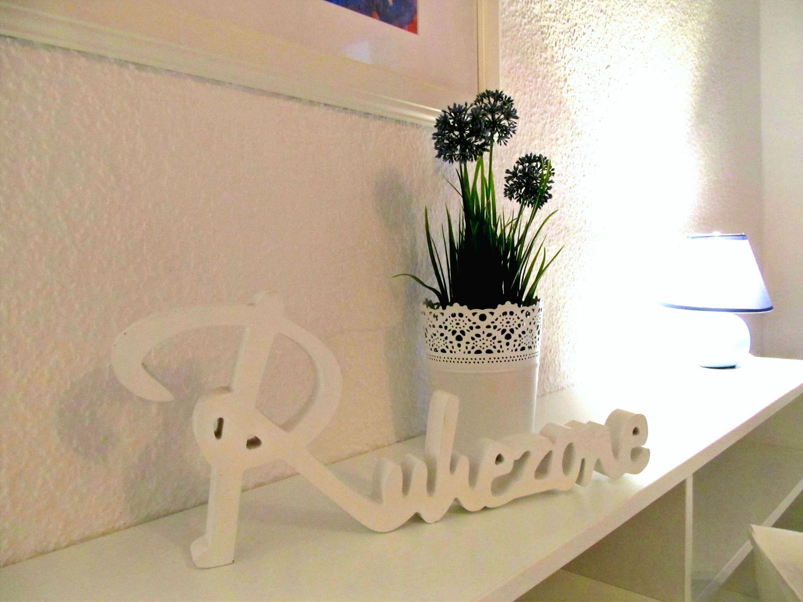 Schreibtisch mit Pflanze und Lampe in weißer Umgebung