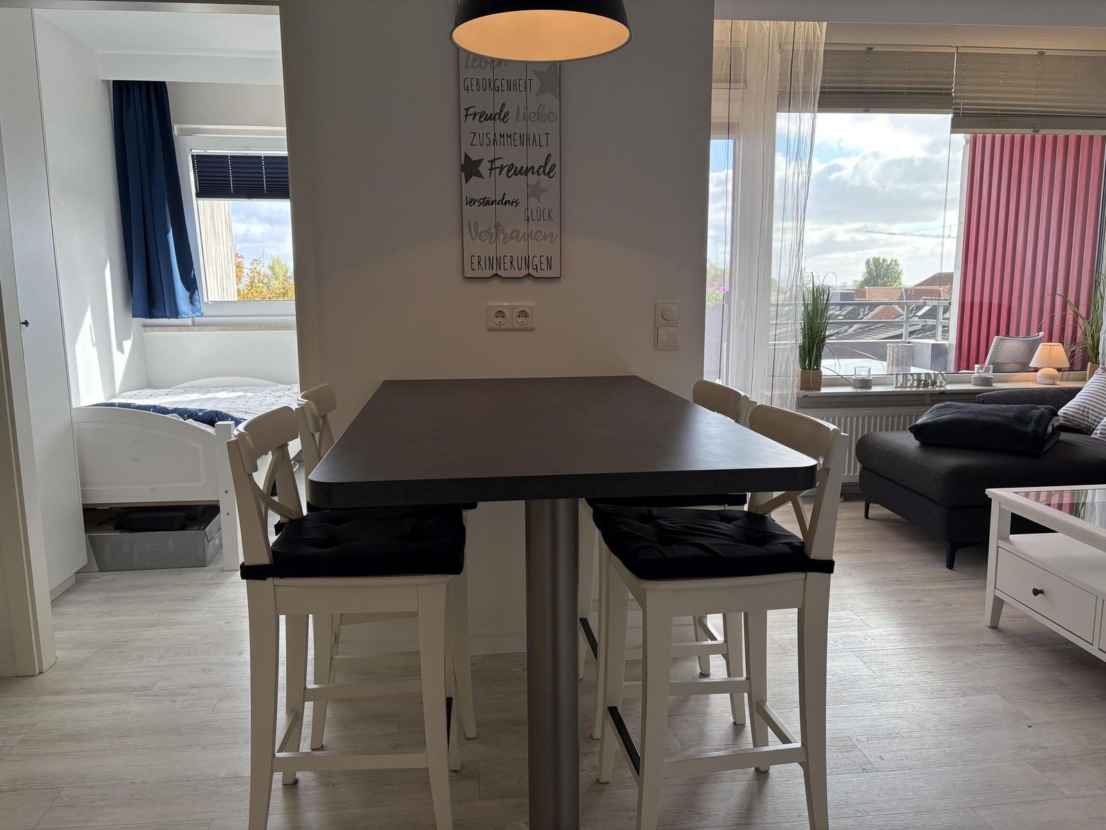 Essbereich mit Tisch und Stühlen. Wohnbereich mit Sofa und Balkonansicht.