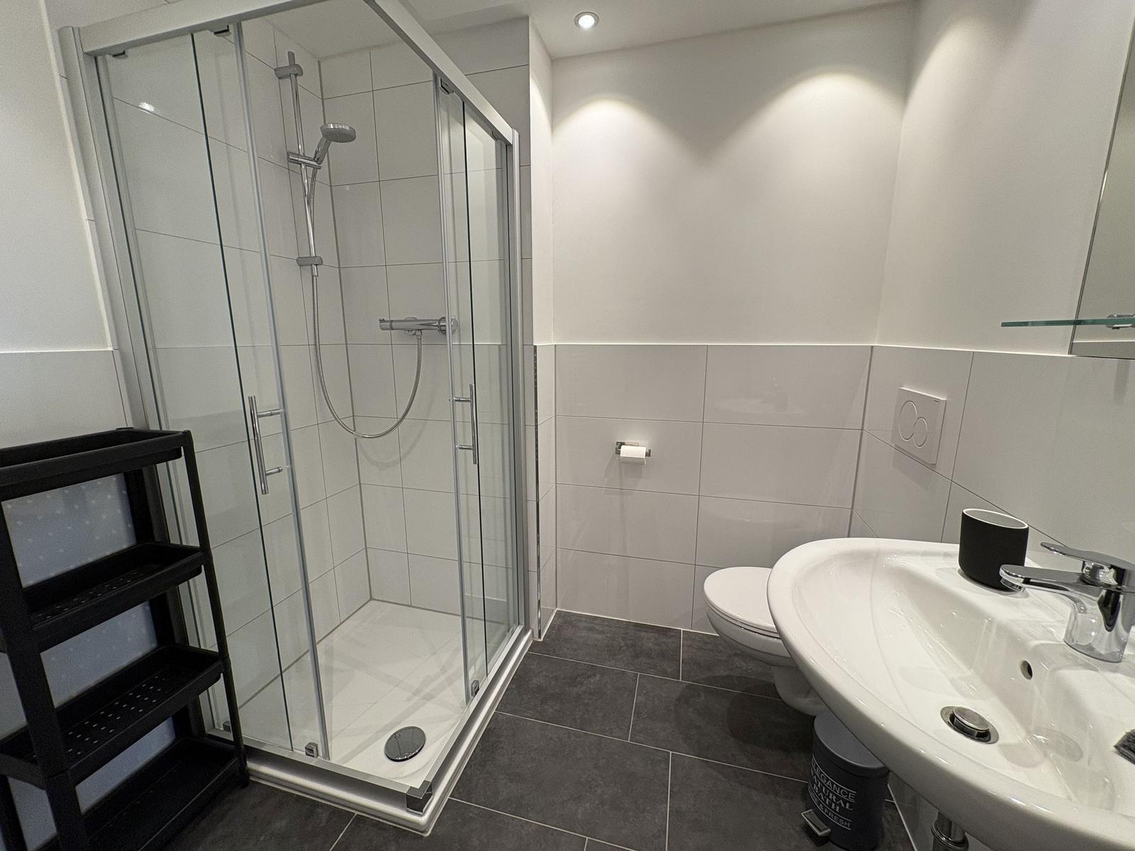 Badezimmer mit Dusche, Toilette und Waschbecken.