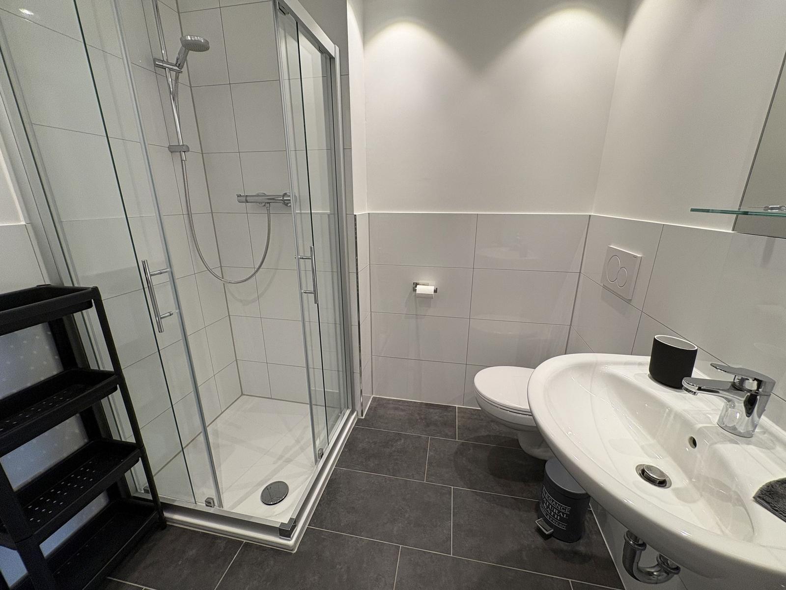 Badezimmer mit Dusche, Toilette und Waschbecken.