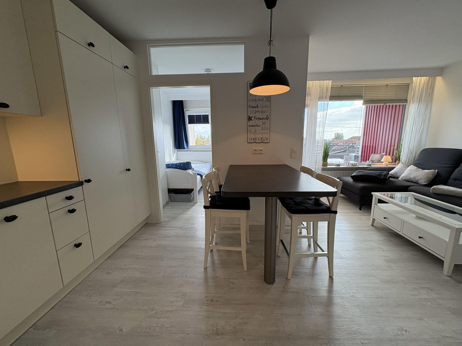 Essbereich mit Tisch und Stühlen. Küche, Wohnzimmer und Schlafzimmer sichtbar.