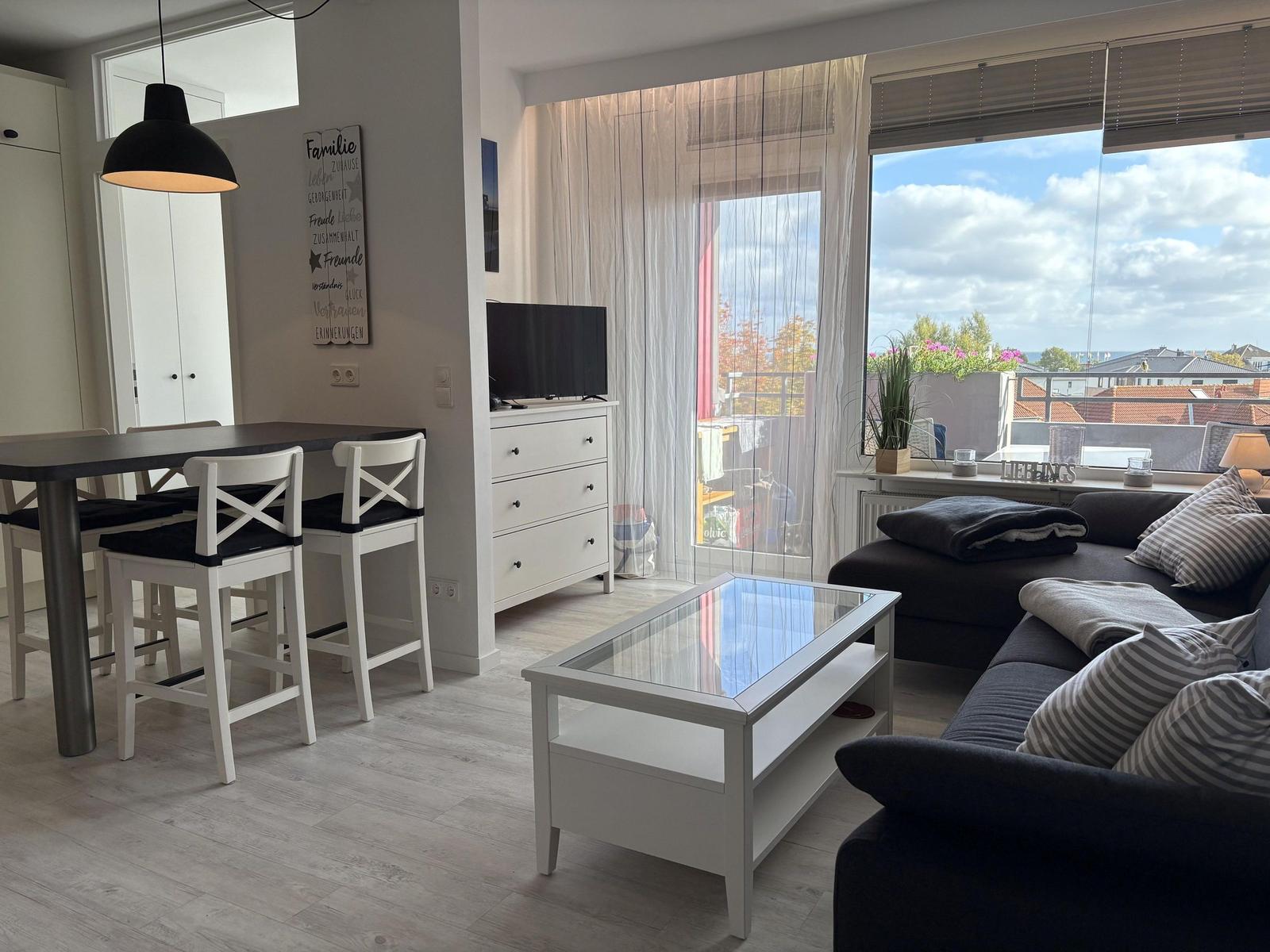Wohn- und Essbereich mit Balkonblick. Schwarz-weiße Einrichtung.