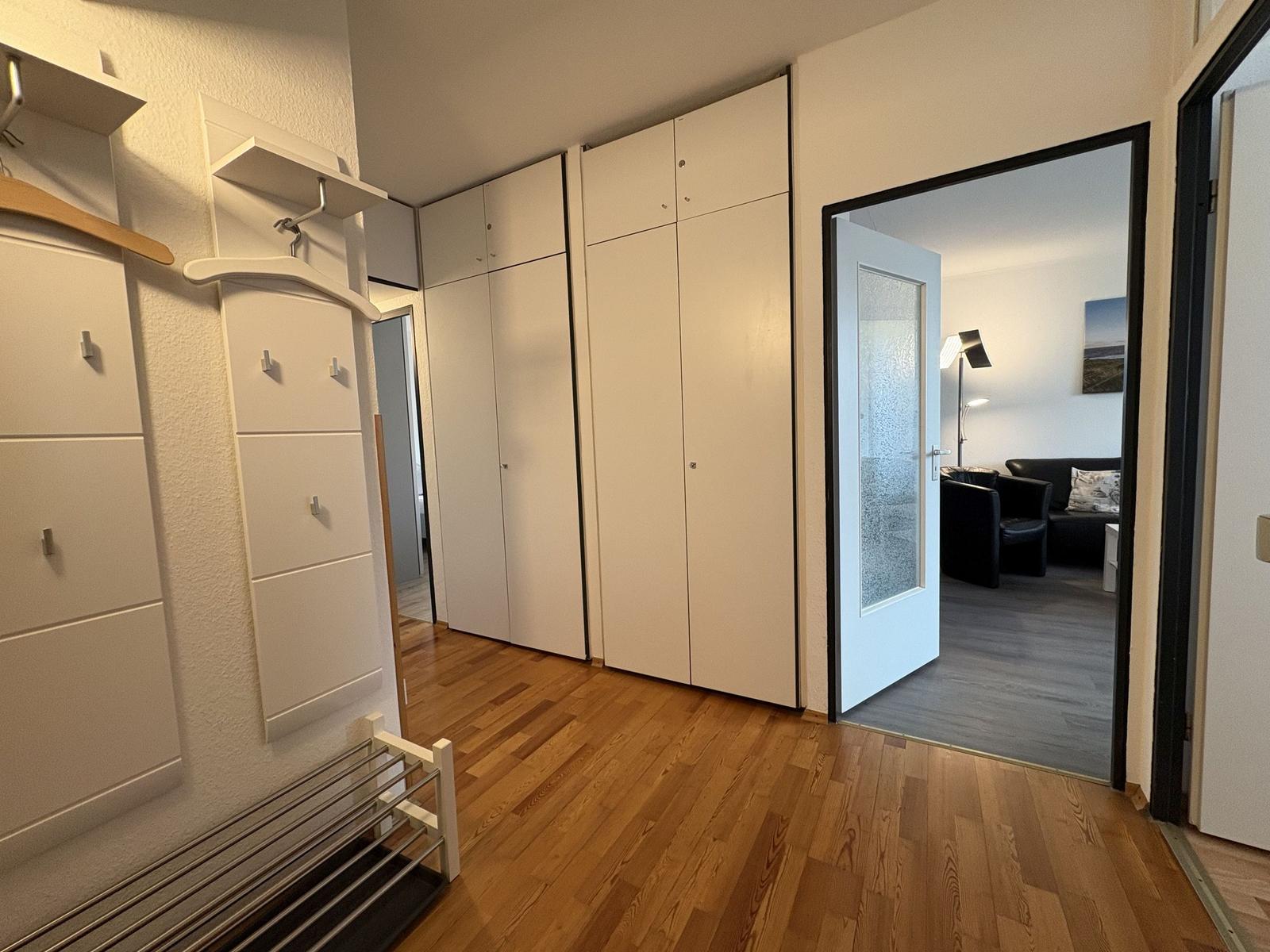 Schlafzimmer mit Kleiderschrank und Blick in Wohnzimmer.