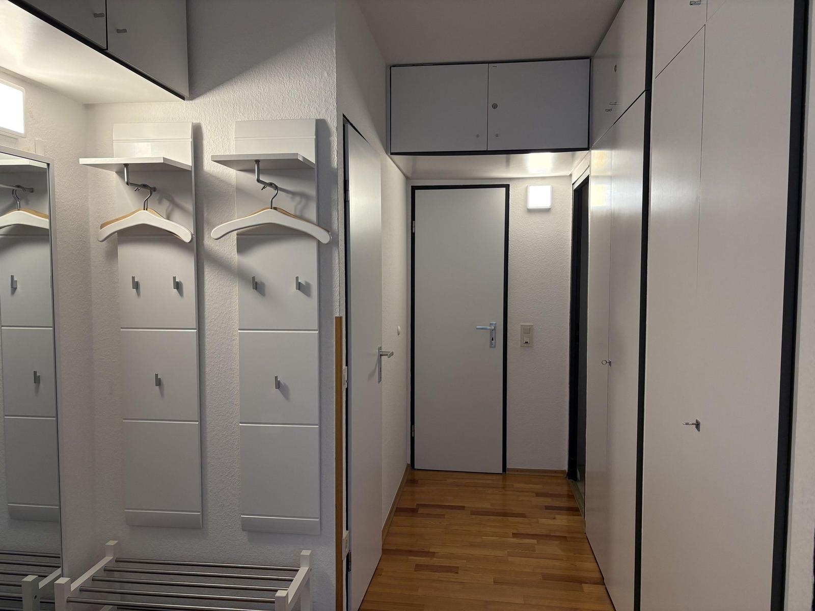 Flur mit Schränken, Garderoben und Holzboden.