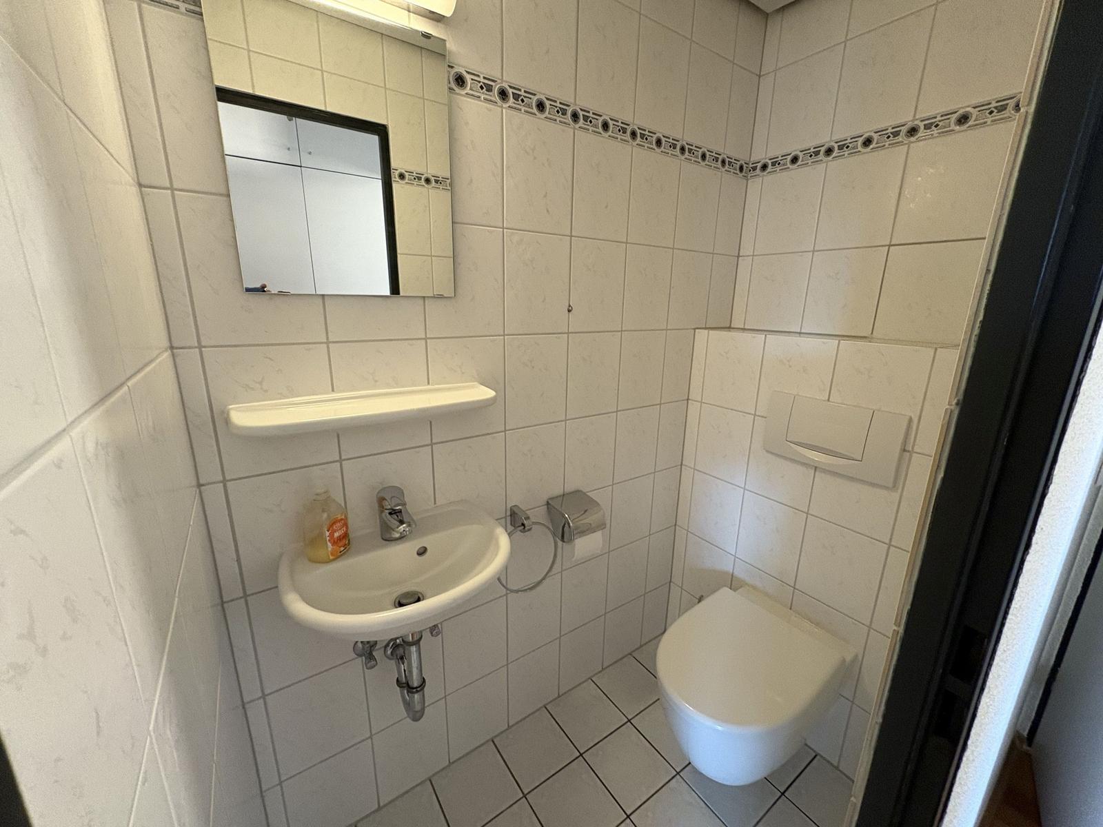 Badezimmer mit Waschbecken, Spiegel und Toilette