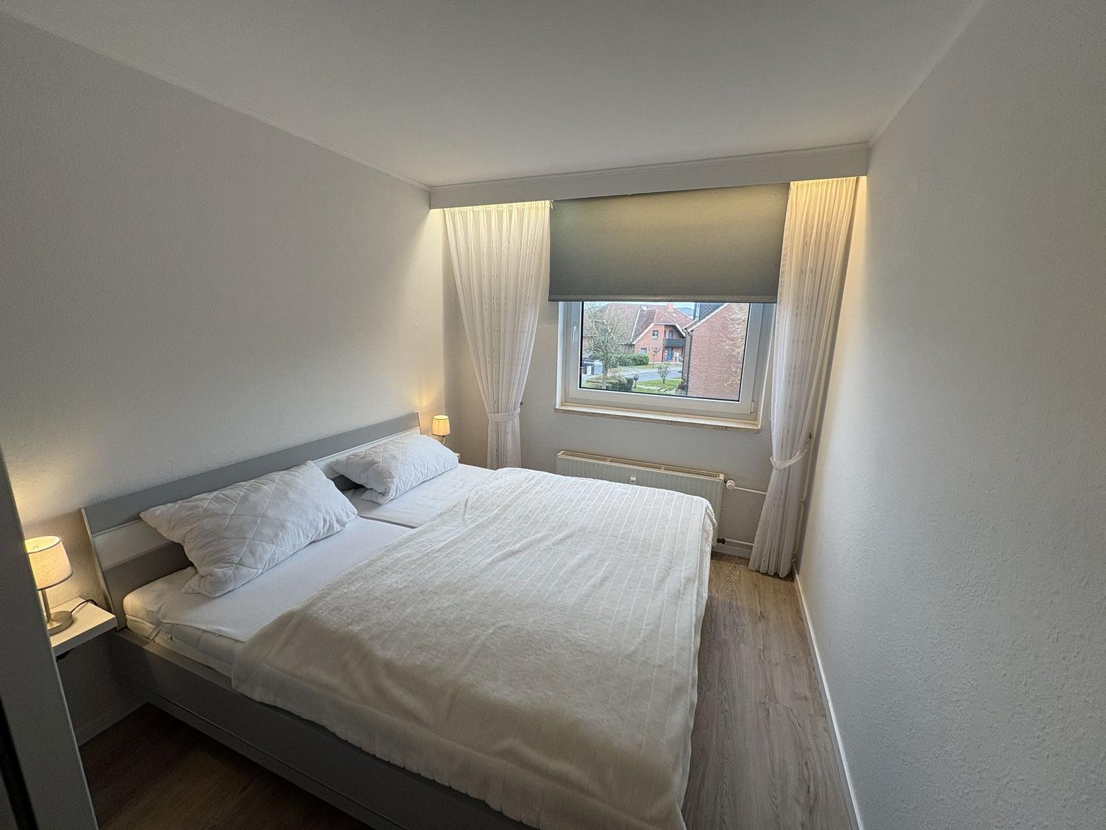 Schlafzimmer mit Doppelbett, Fenster und Nachttischlampen.