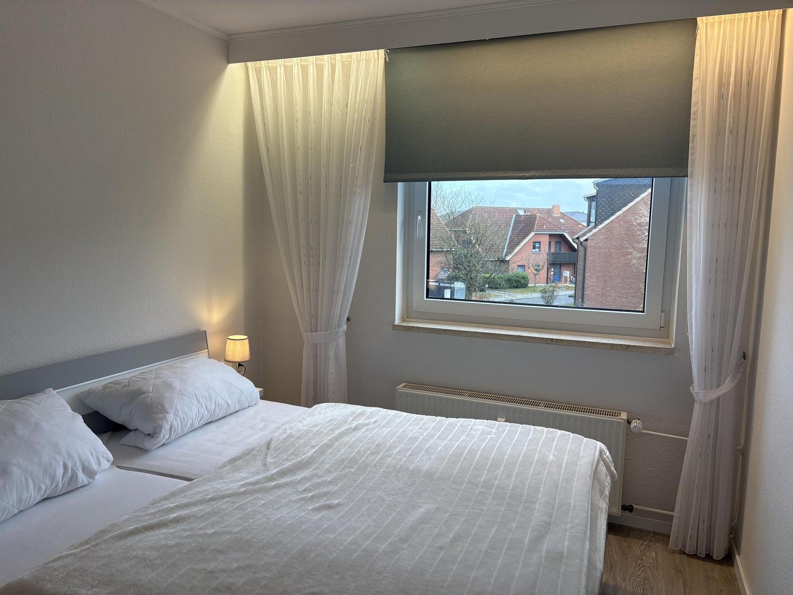 Schlafzimmer mit Doppelbett, Fenster und Heizkörper.