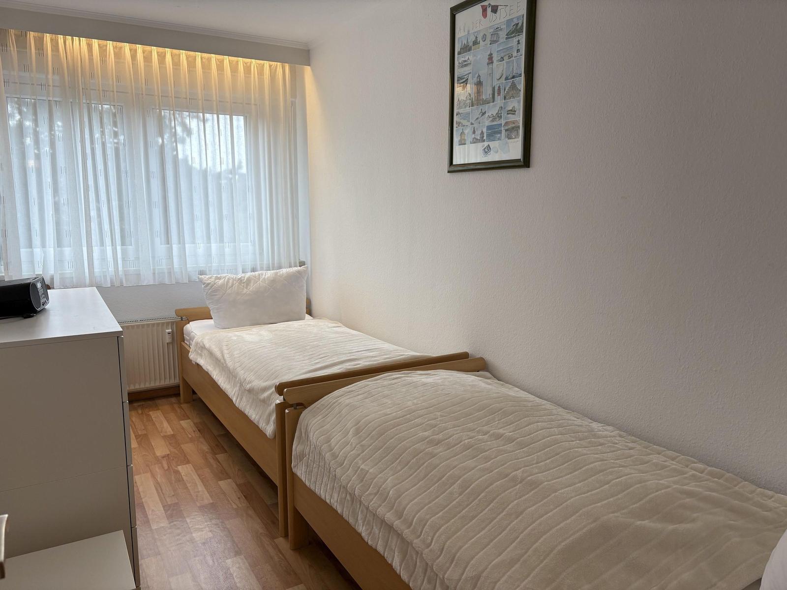 Zwei Einzelbetten, Fenster mit Vorhängen und Wandbild.