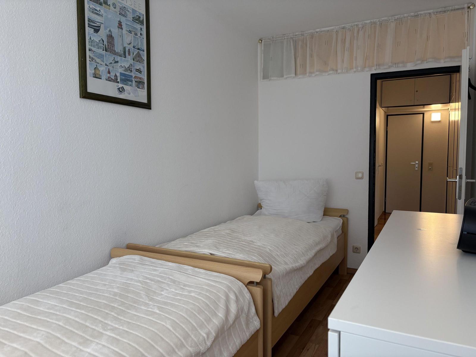 Ein Schlafzimmer mit zwei Einzelbetten, einem Schreibtisch und einer Wanddekoration.