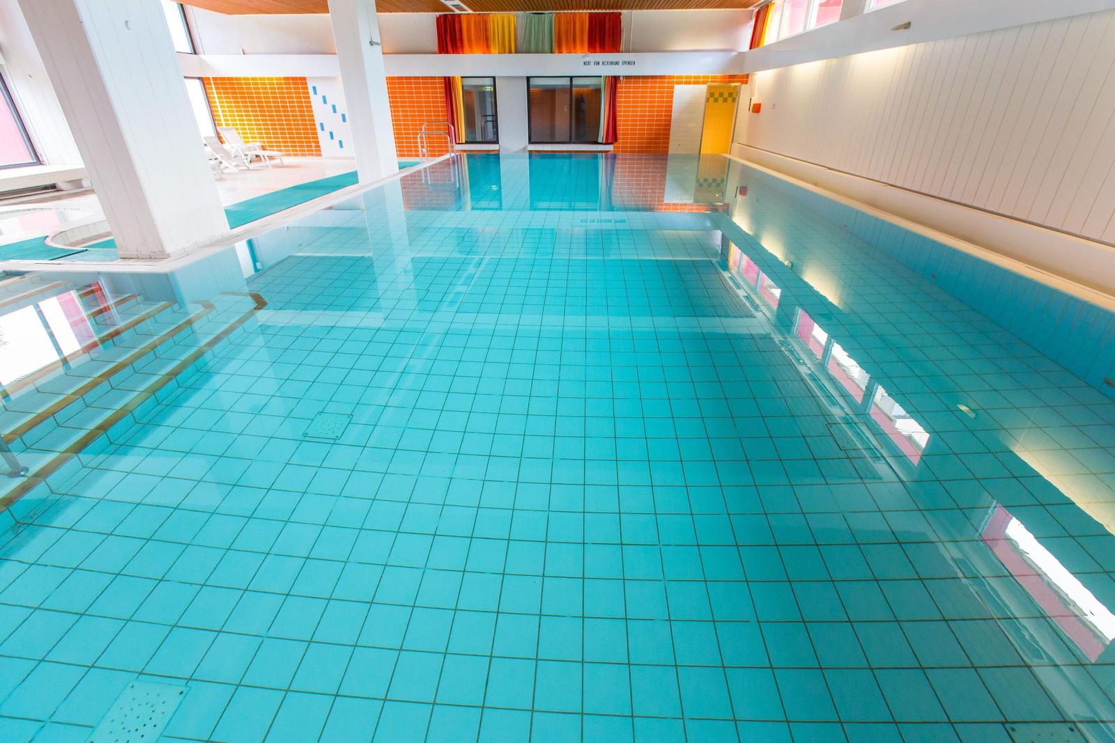 Großer Innenpool mit blauen Fliesen und moderner Beleuchtung.