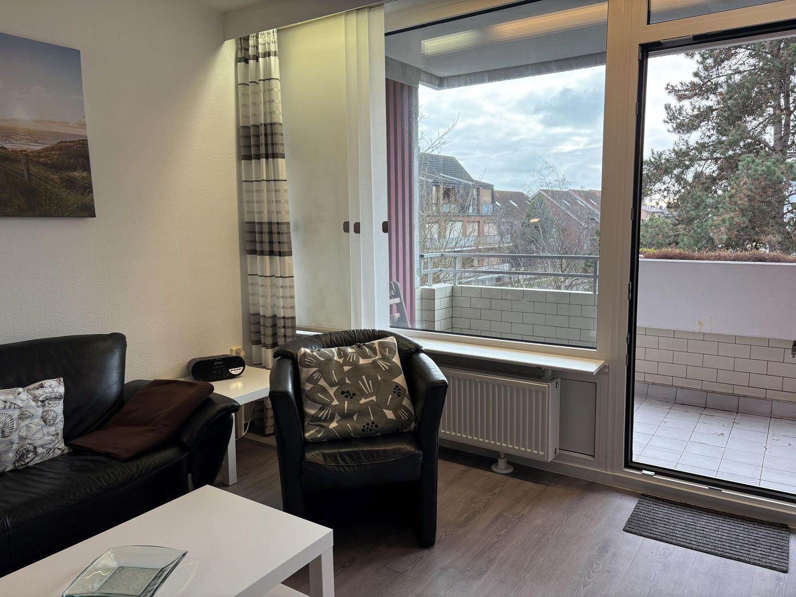 Wohnzimmer mit Sitzgelegenheiten und Balkonansicht.