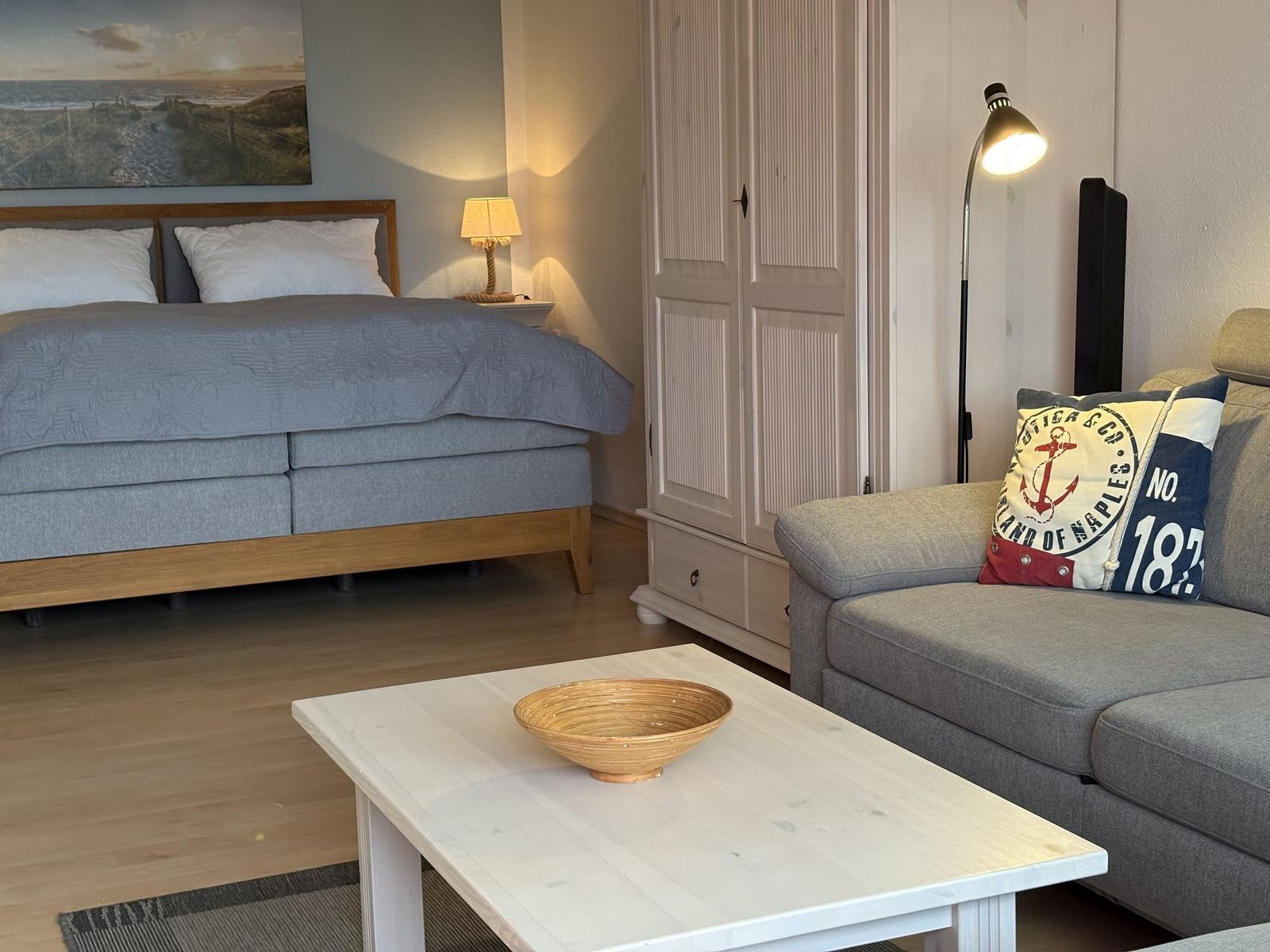 Schlafzimmer mit Bett, Sofa und Kleiderschrank. Tisch mit Schale davor.