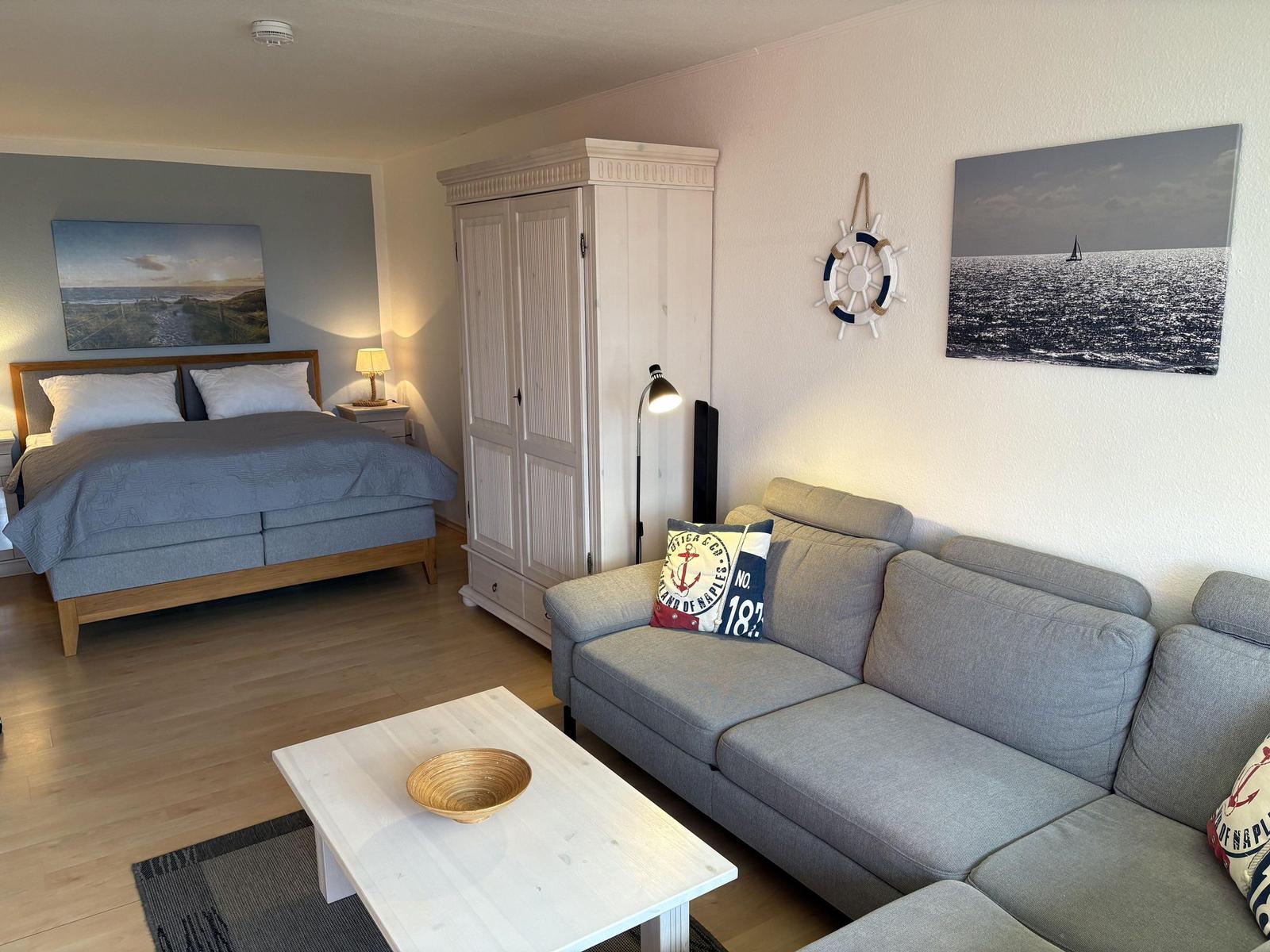 Ein Schlafzimmer mit Sofa, Kleiderschrank und Wandbildern.