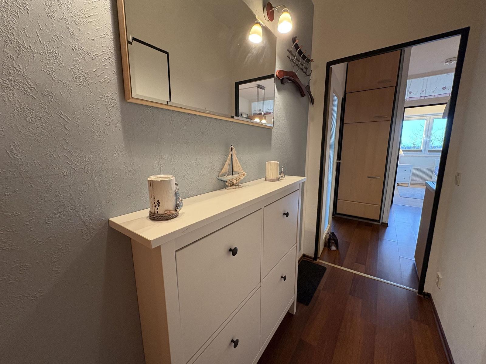 Eingangsbereich mit Schrank, Spiegel und Tür zum Schlafzimmer.