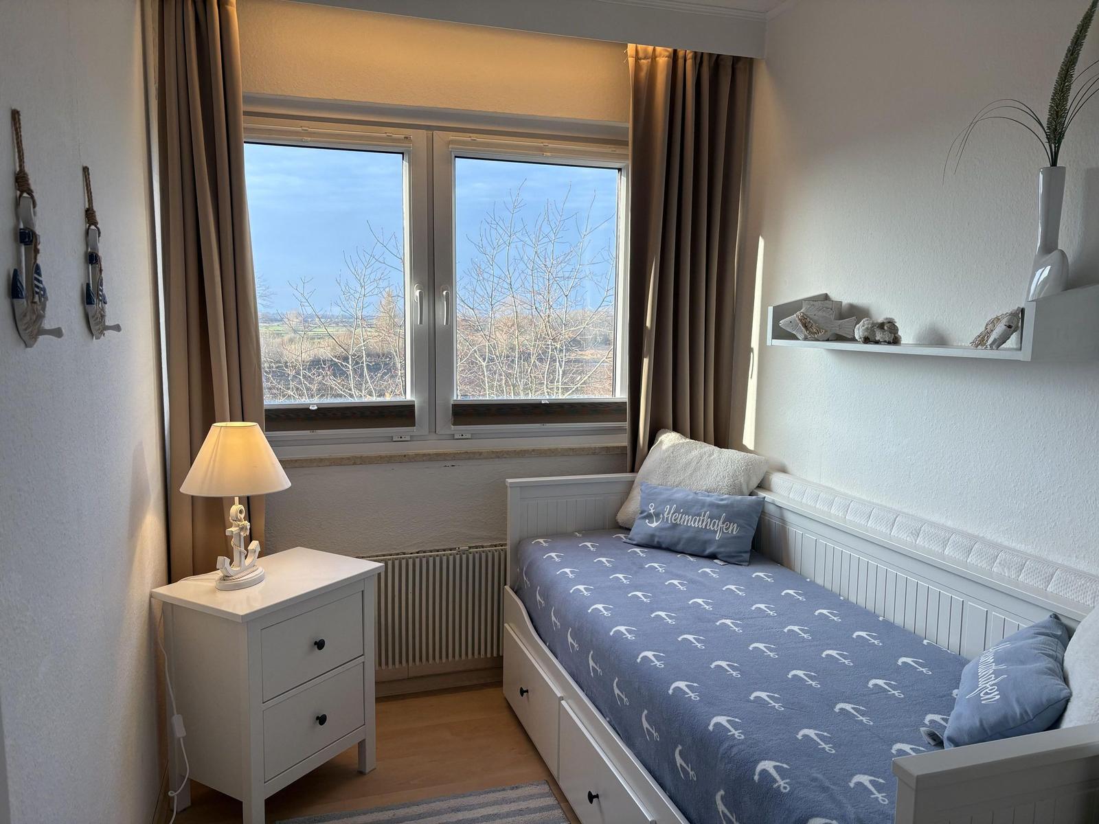 Ein Schlafzimmer mit Bett, Nachttisch und Fenster mit Blick auf Landschaft.