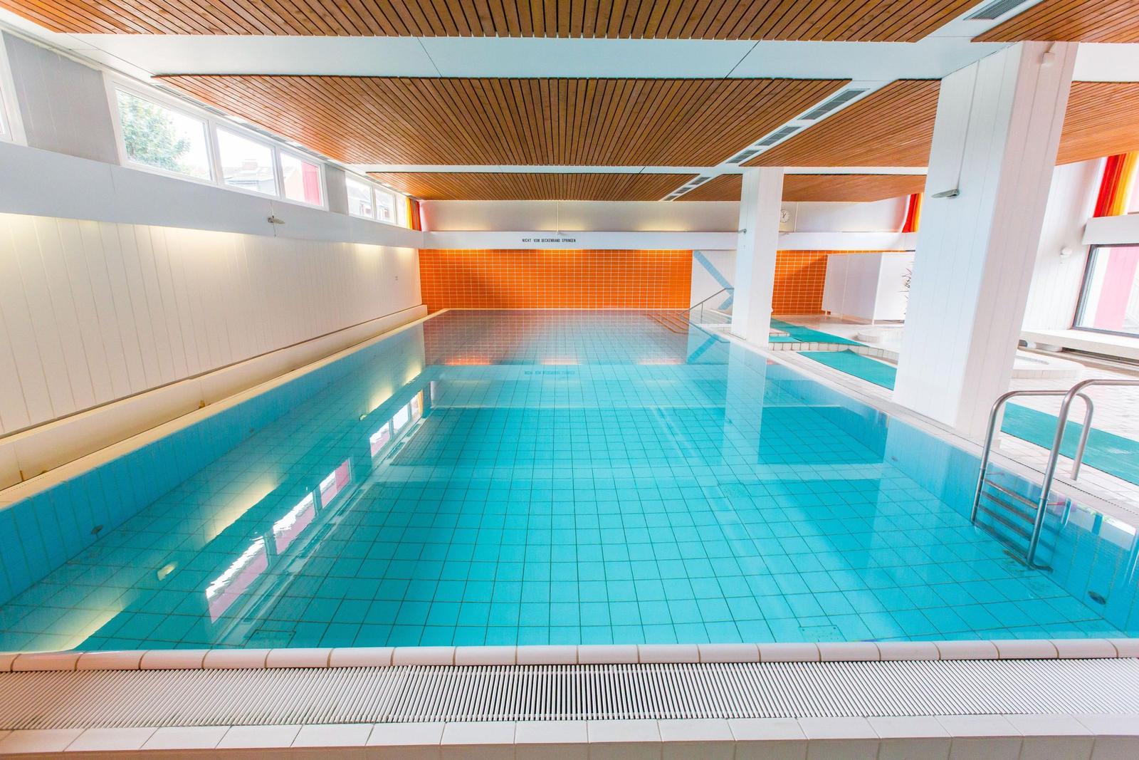 Großer Innenpool mit blauen Fliesen und Holzdecke