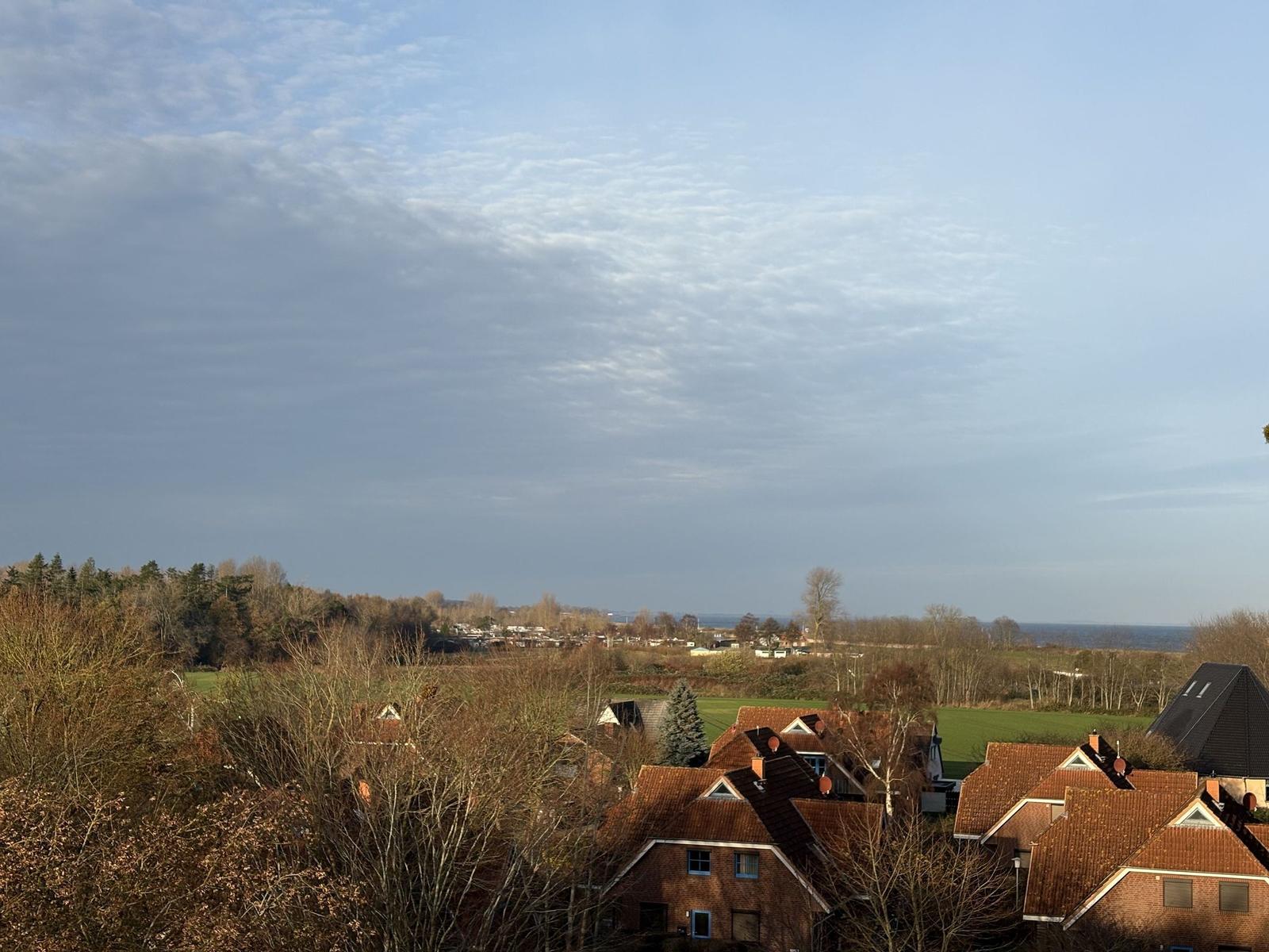 Panoramablick auf Dörfer, Felder und Horizont unter bewölktem Himmel.