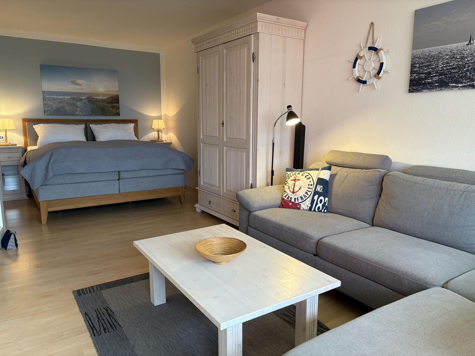 Schlafzimmer mit Bett, Sofa und Kleiderschrank. Wanddekoration und Holzboden.