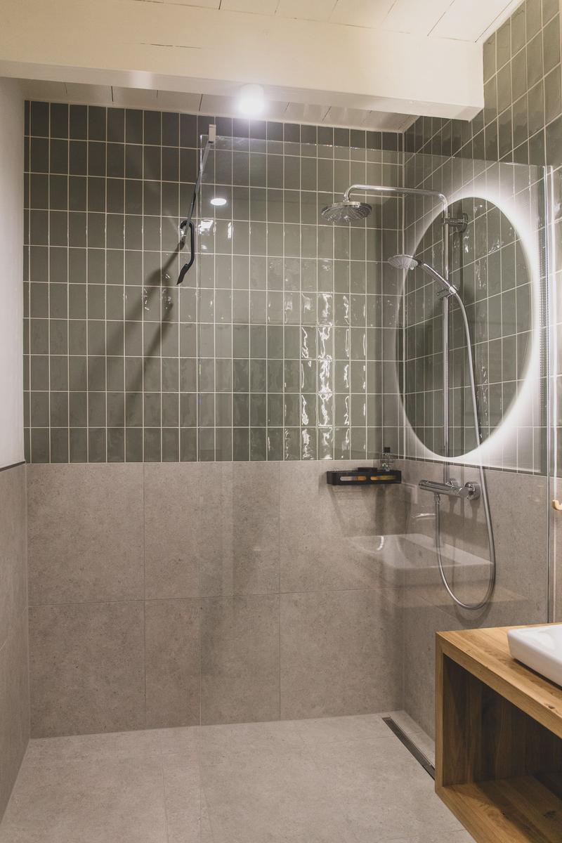Duschkabine mit Duschkopf und Handbrause. Holzwaschbecken und Spiegelfläche.