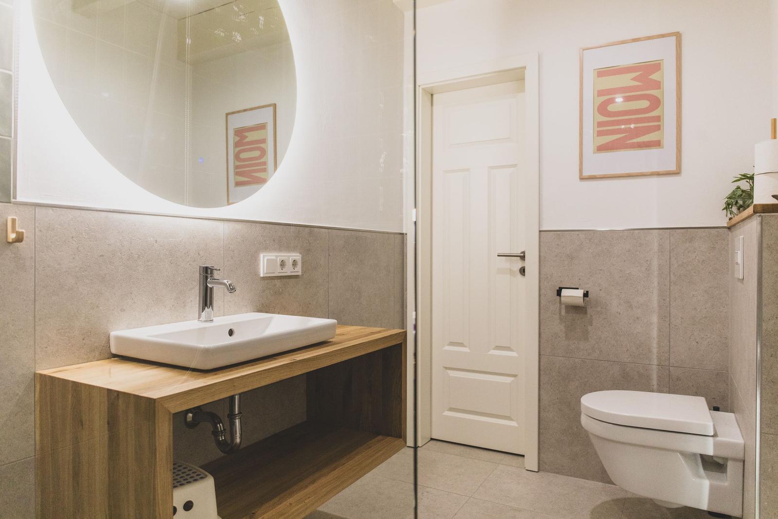 Bad mit Waschtisch, Toilette und runden Spiegel.