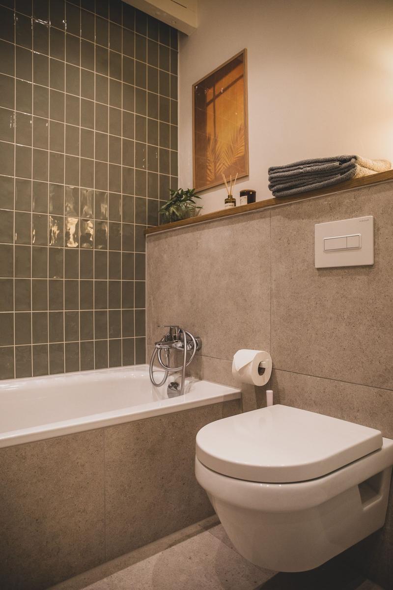 Bad mit Badewanne, Toilette und Holzregal mit Handtüchern.