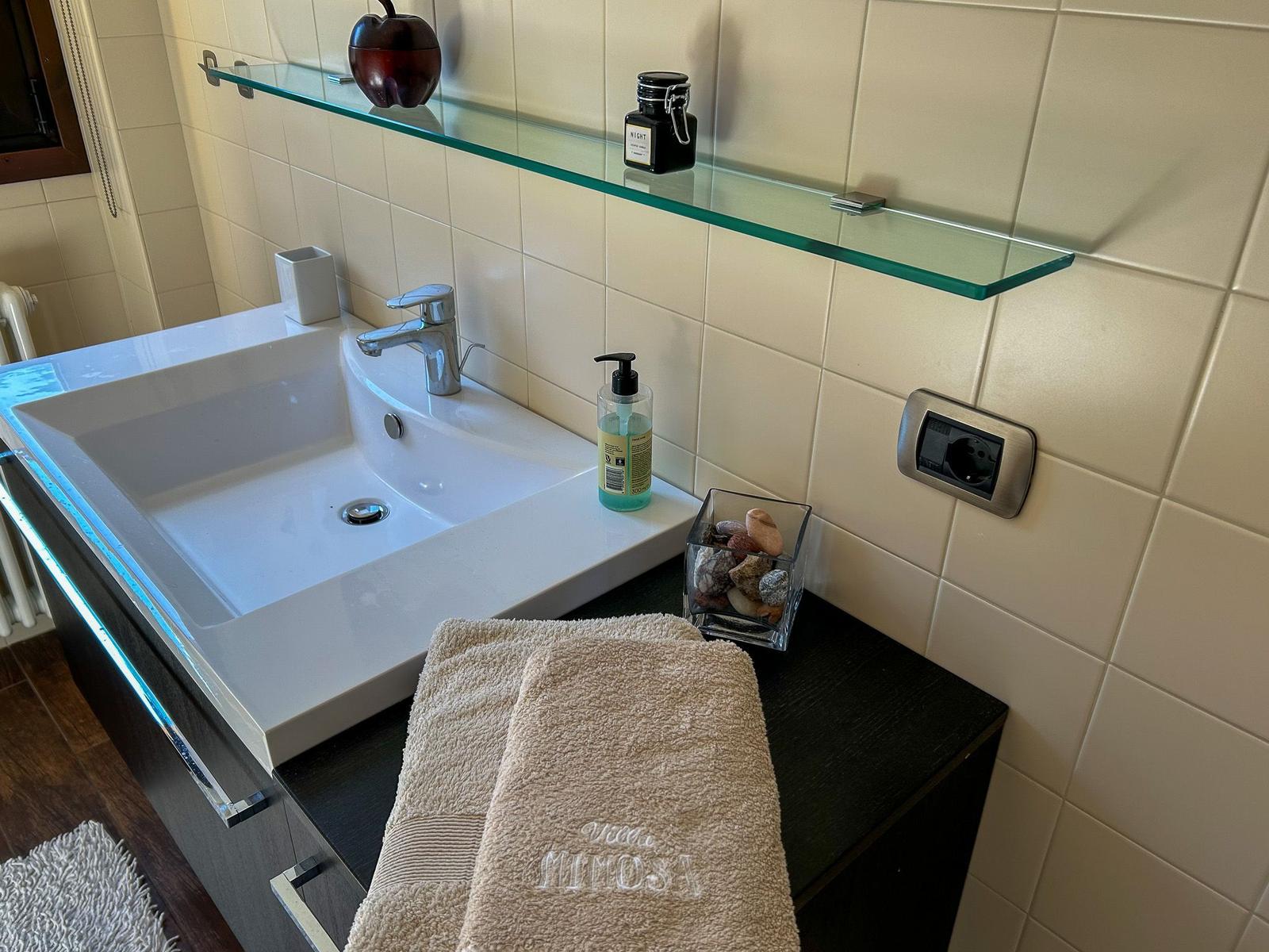 Sink with mirror, towel, and soap on dark vanity.