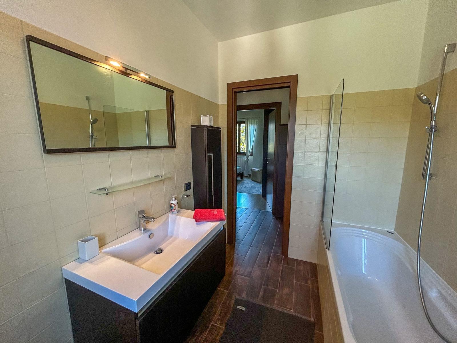Bathroom with bathtub, shower, and sink with mirror
