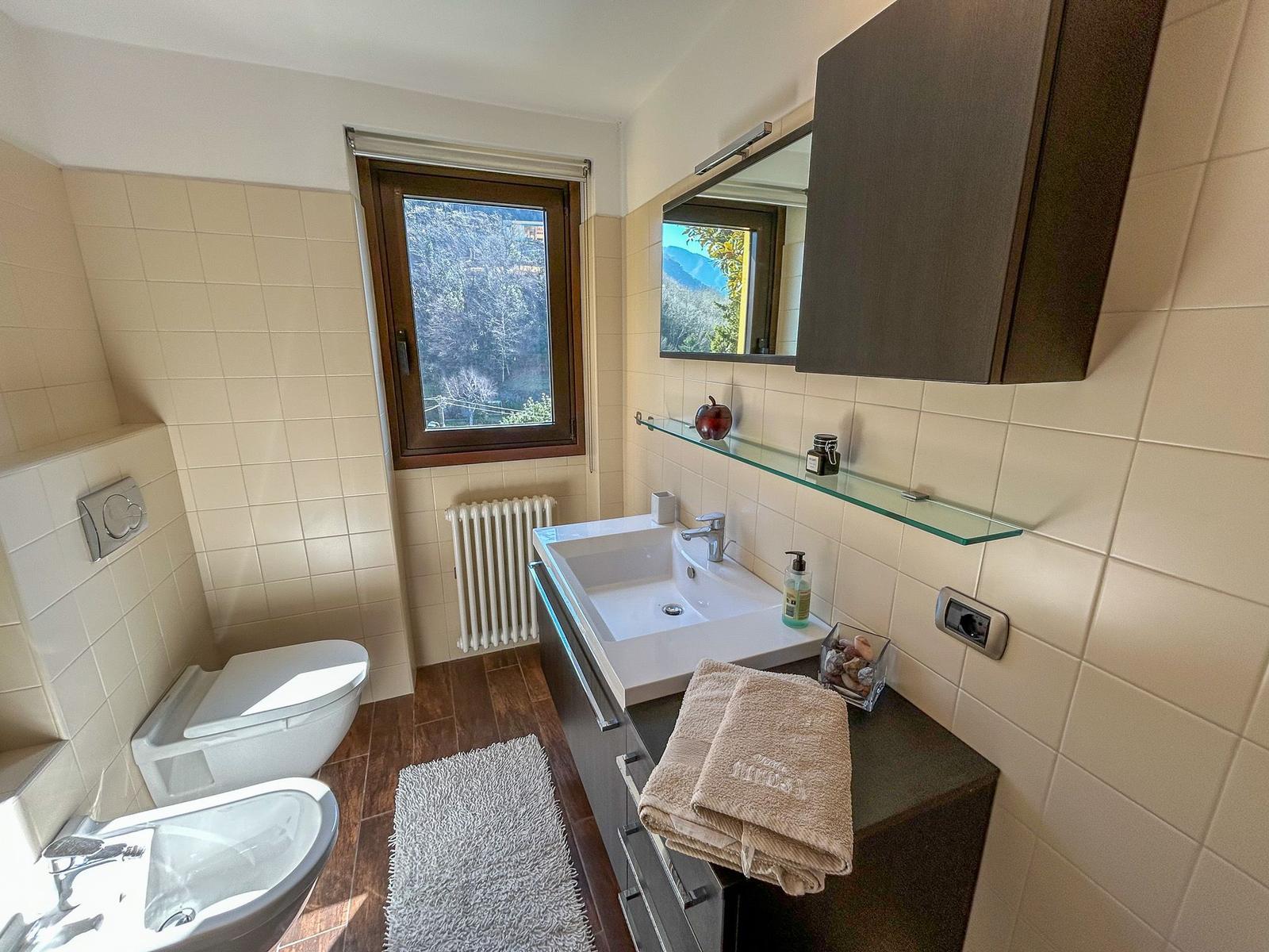 Bathroom with sink, toilet, and bathtub. Window with mountain view.