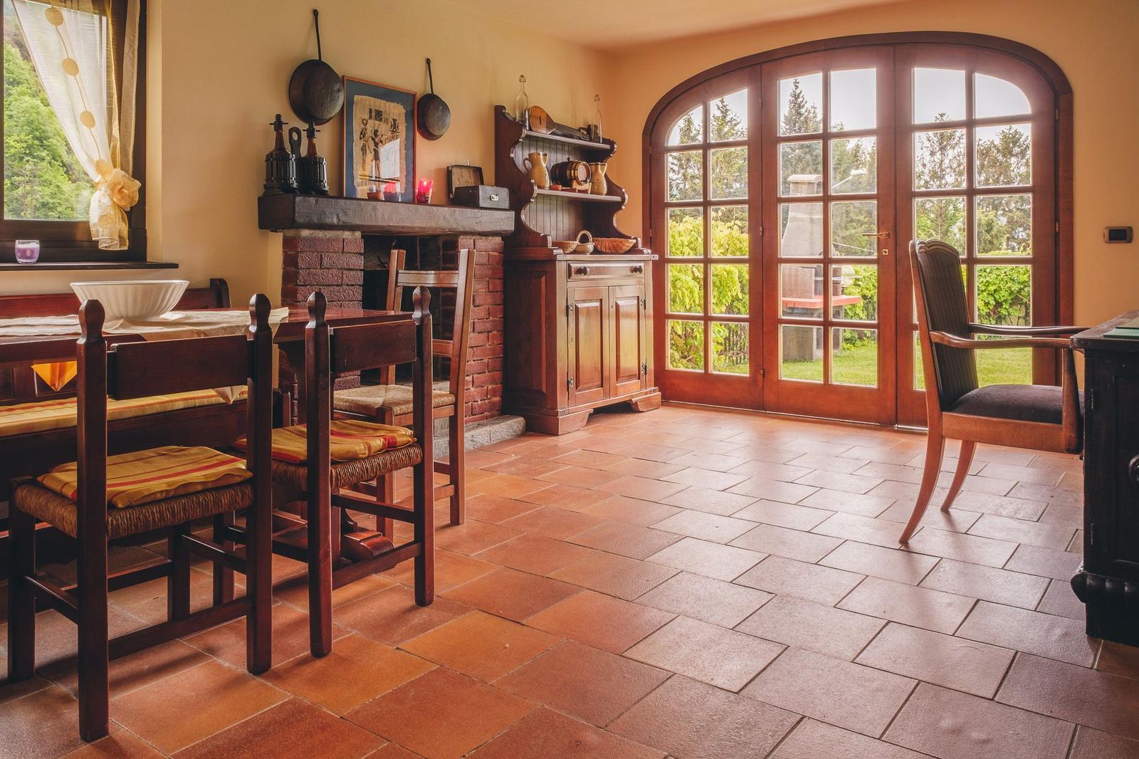 Dining room with wooden furniture, brick fireplace, and garden view.