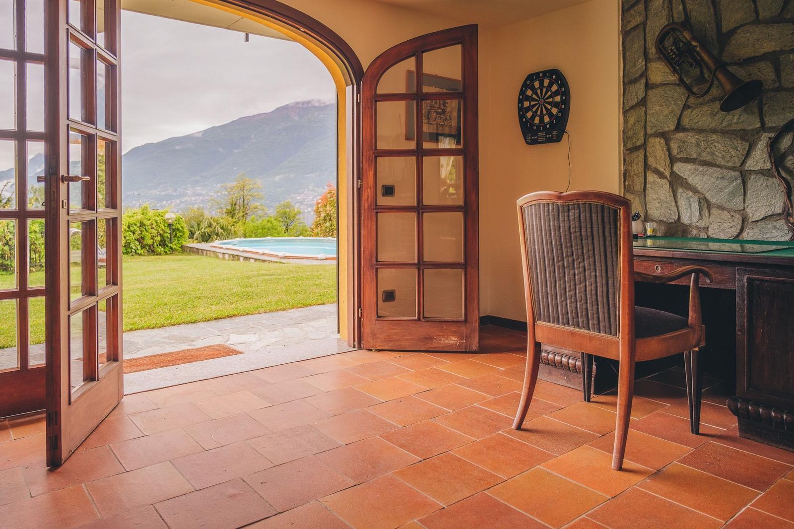 Entrance area with view of pool and mountains. Table, chair, and dartboard.