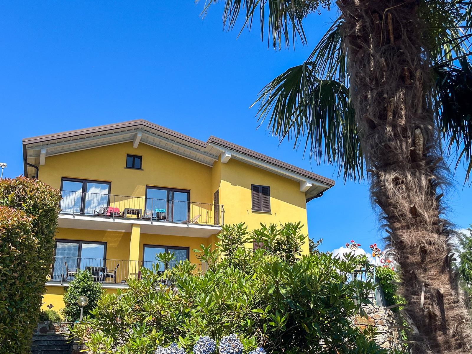 Yellow house with balconies and palm tree against blue sky