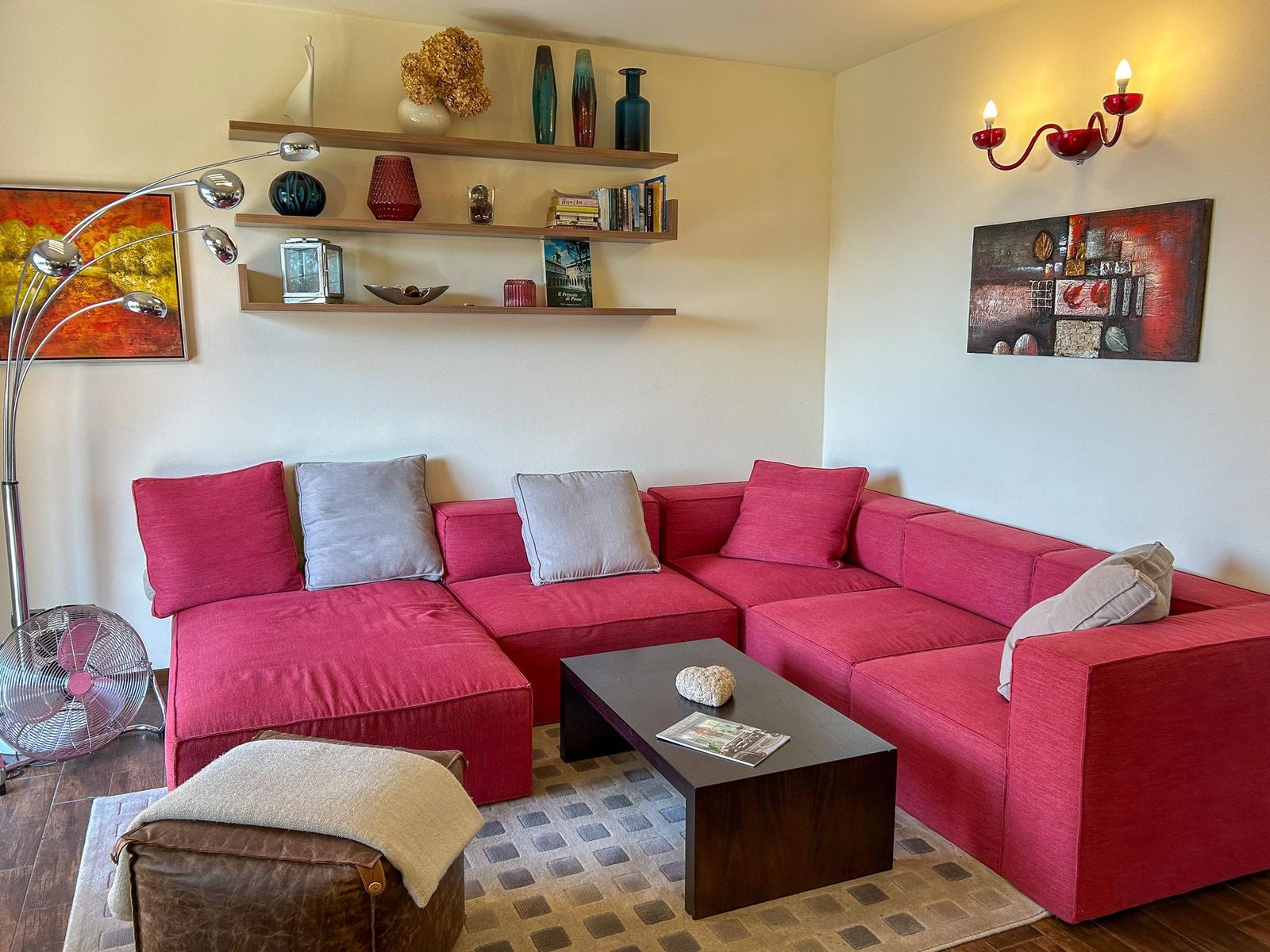 Living room with red sofa, wooden shelves, and coffee table.