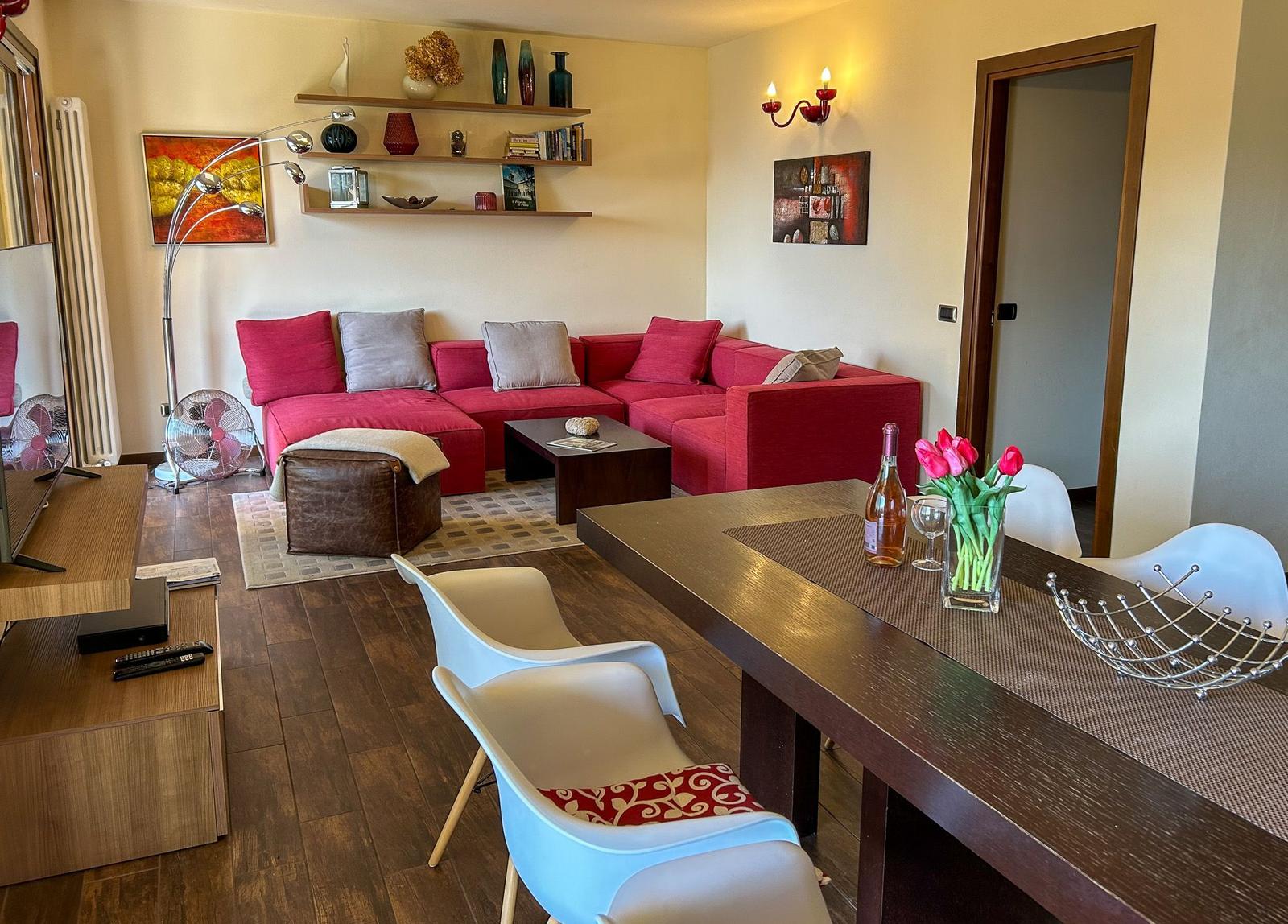 Living and dining area with red sofa, dining table, and TV.