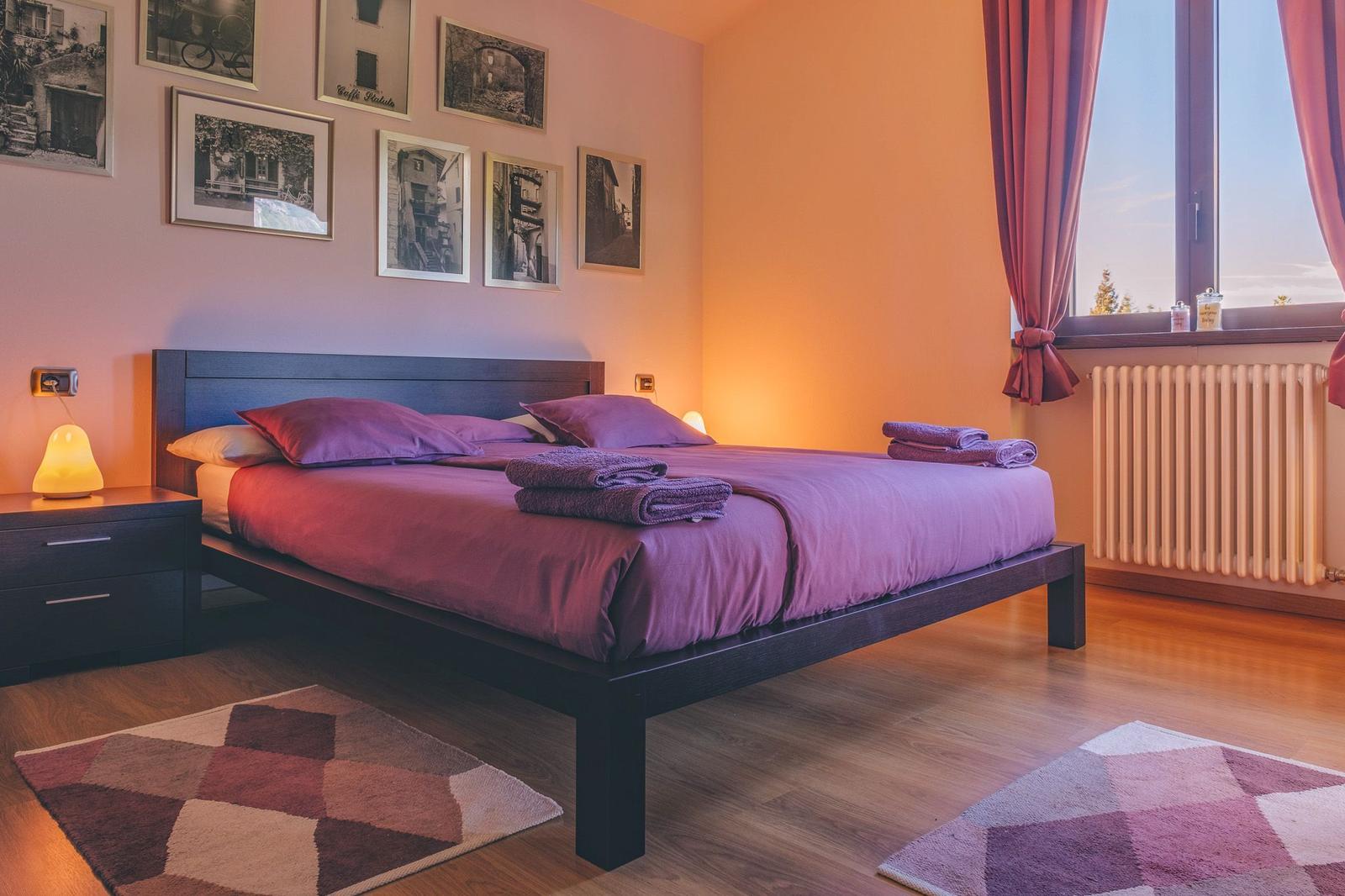 Schlafzimmer mit Bett, Bildern an der Wand und Fenster mit Blick.