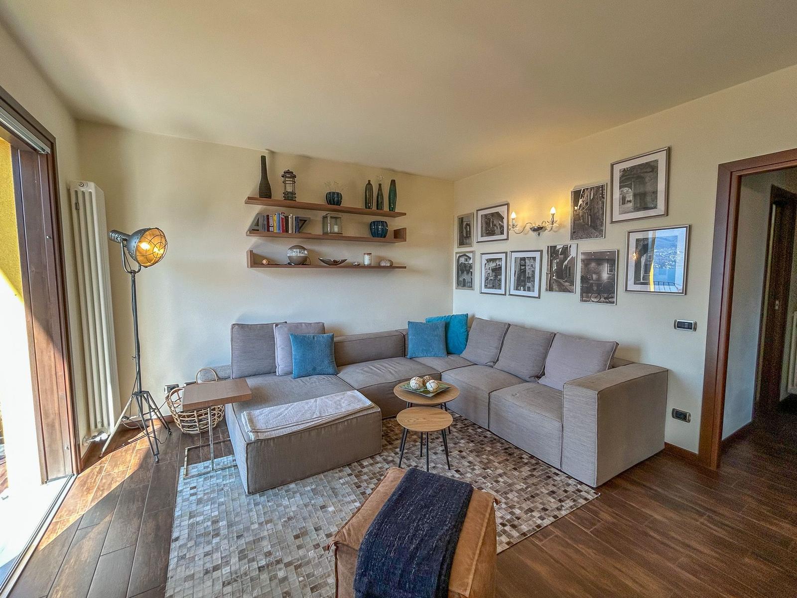 Wohnzimmer mit Ecksofa, Wandregalen und Bildern an der Wand.