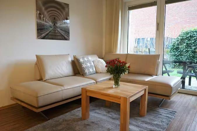 Wohnzimmer mit L-förmigem Sofa, Holztisch und Blick auf Balkon