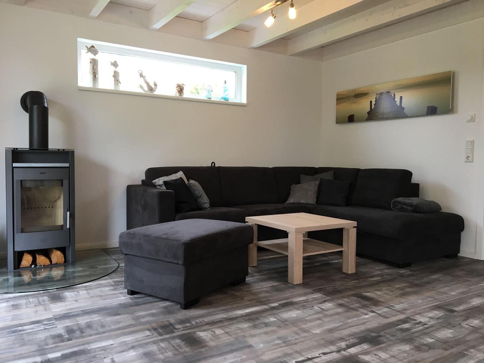 Wohnzimmer mit Ecksofa, Kamin und Holzboden