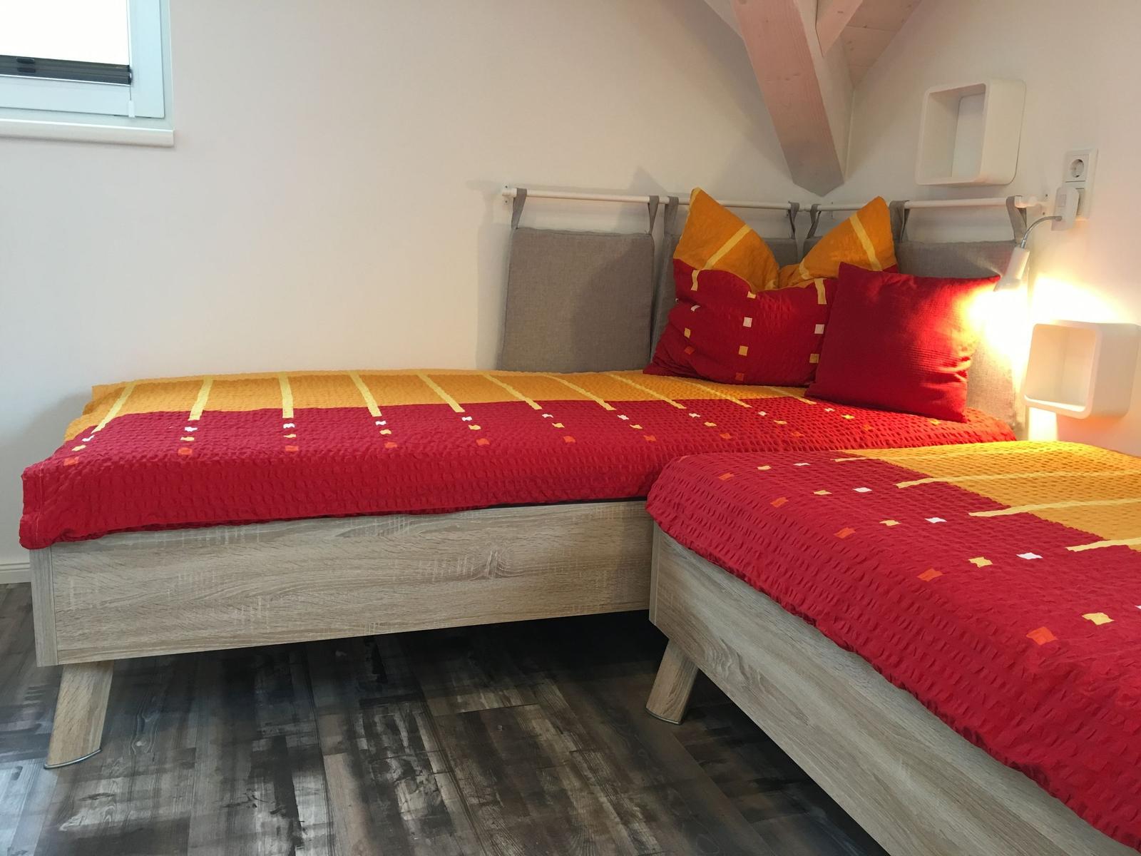 Zimmer mit zwei Betten, Holzboden und Dachschrägen.