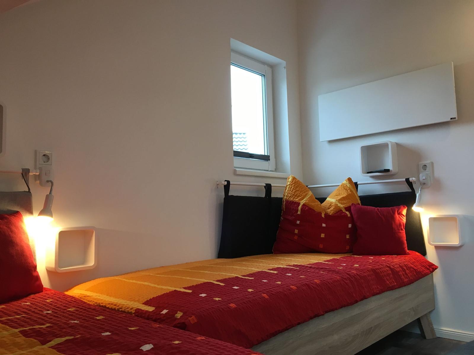 Schlafzimmer mit Bett, Fenster und Wandregalen.