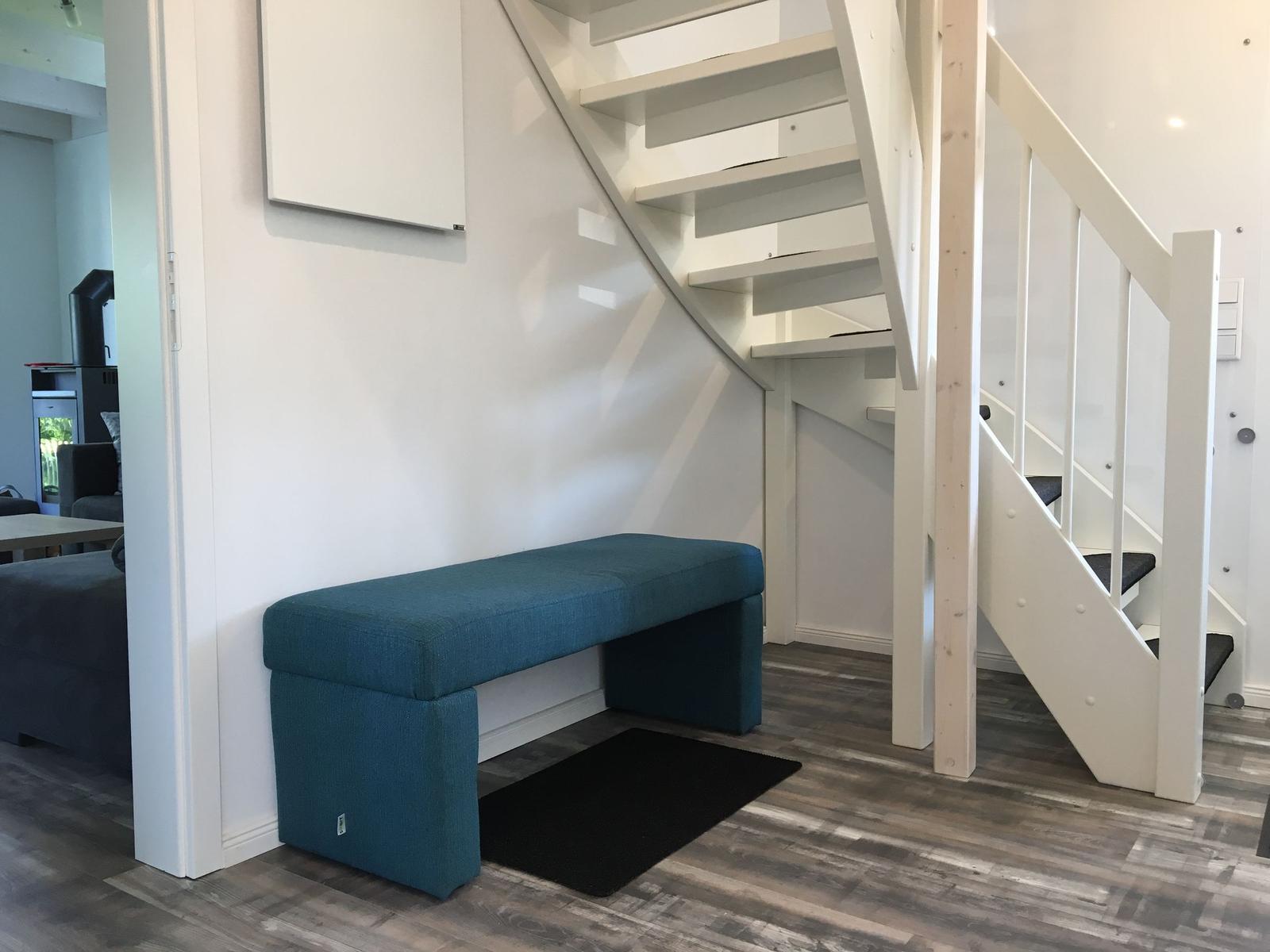 Blauer Sitzbank unter Treppe mit Holzboden und weißer Wand