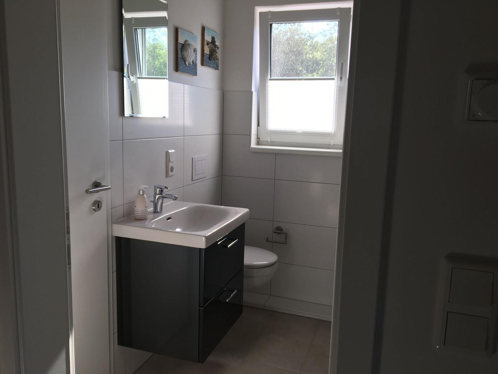 Badezimmer mit Waschbecken, Toilette und Fenster