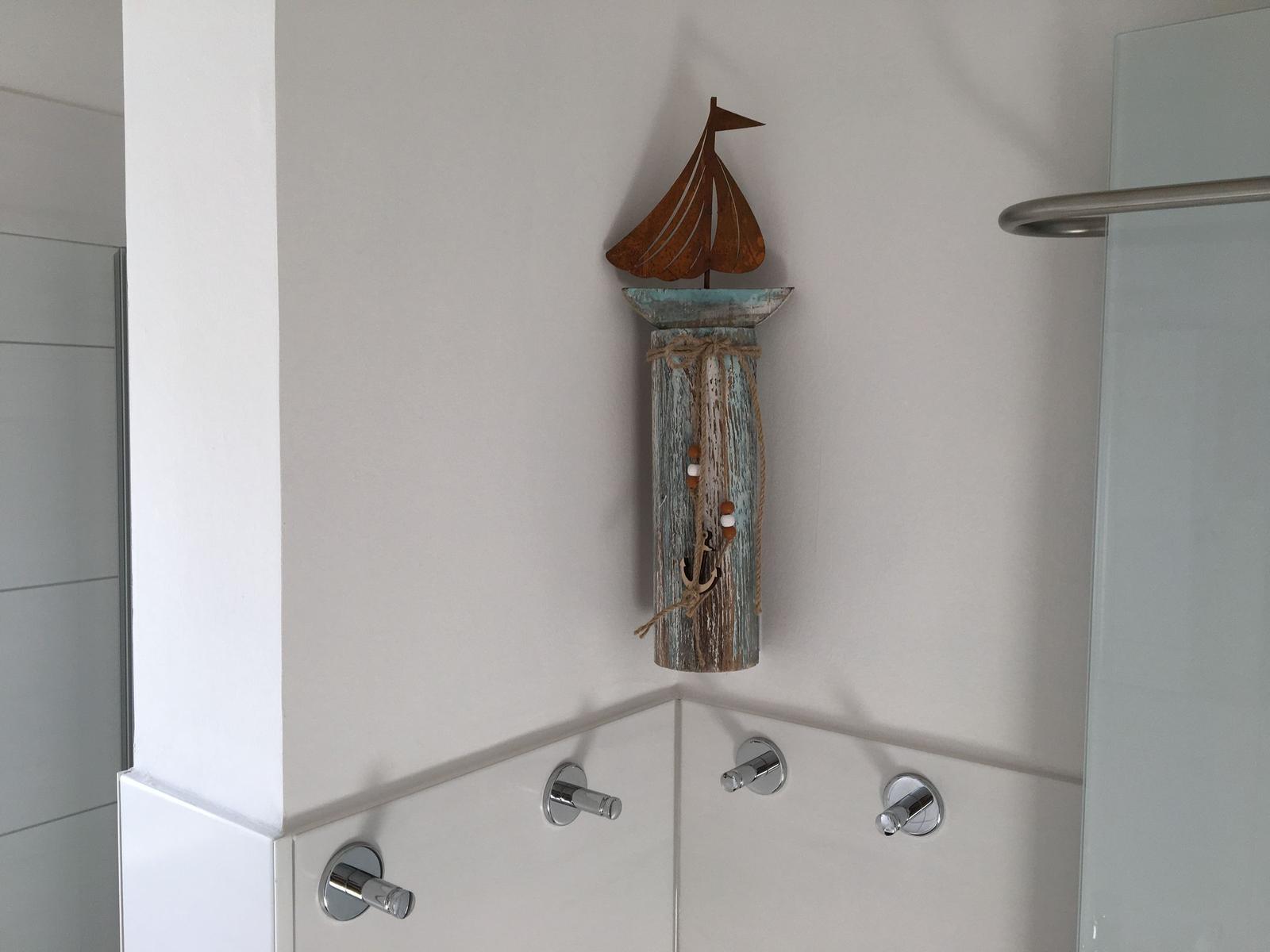 Duschbereich mit Segelboot-Dekoration an der Wand.