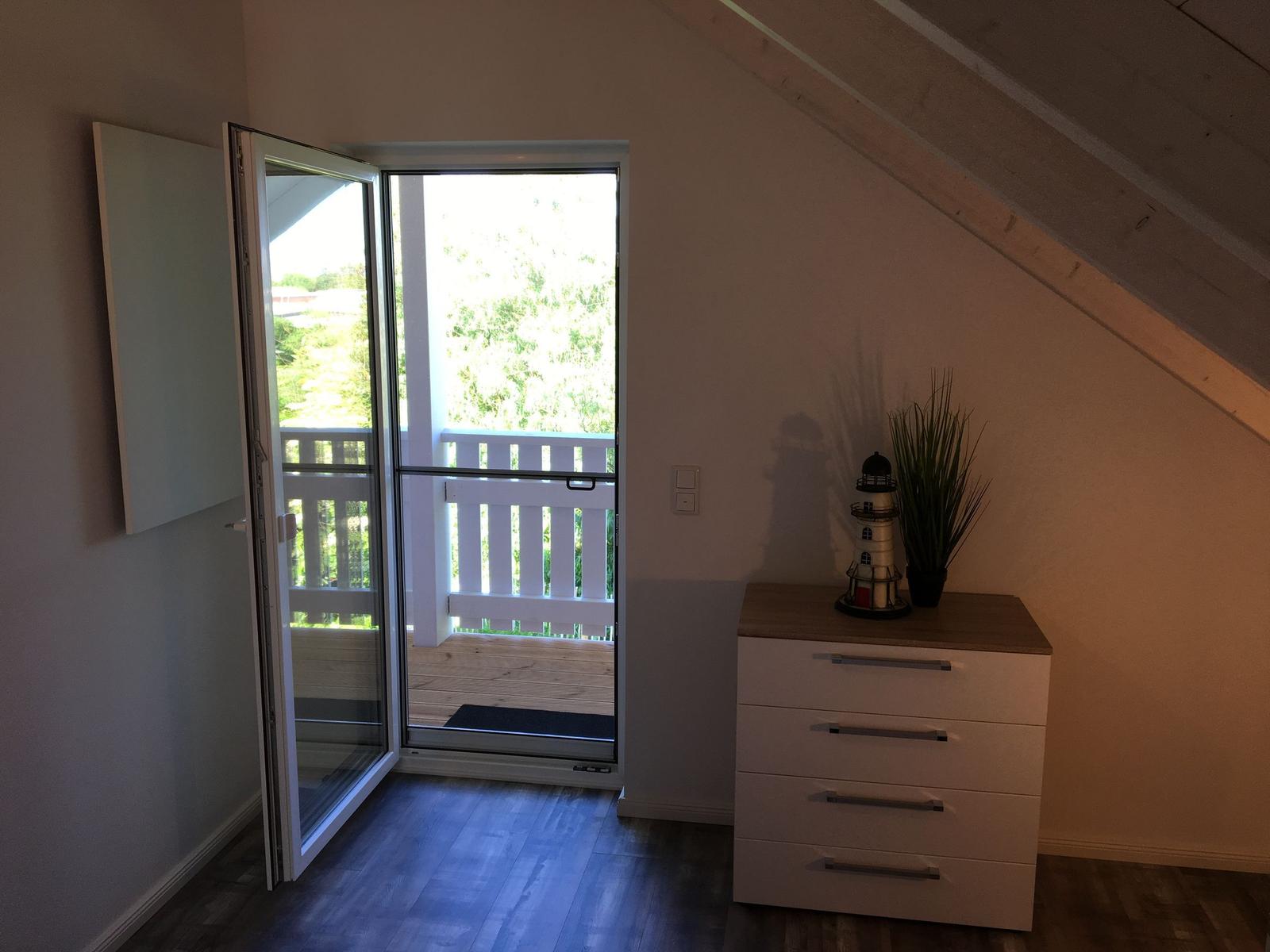 Zimmer mit Schlafzimmerausstattung und Balkonzugang.