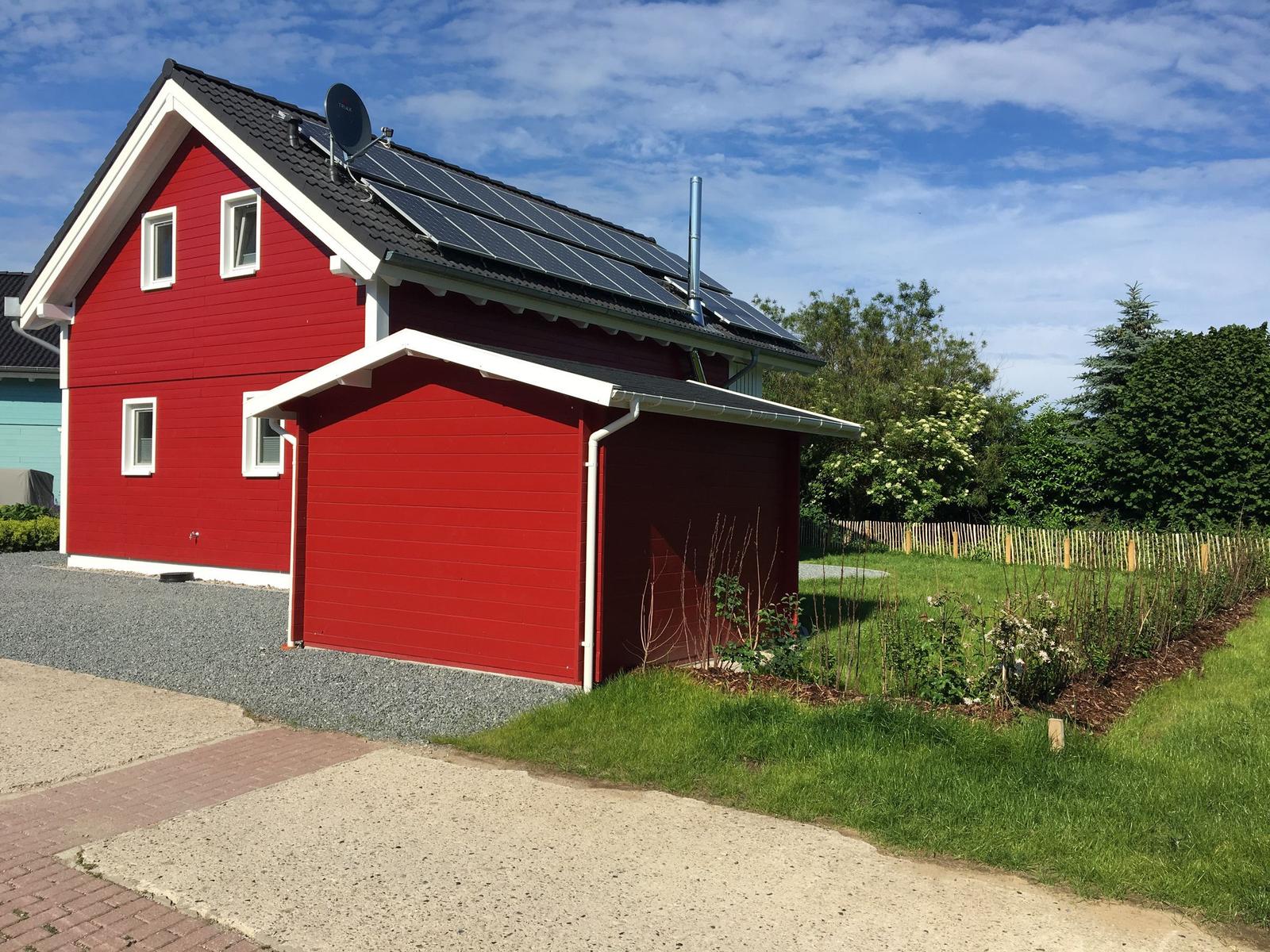 Rotes Haus mit Solaranlage und Garten
