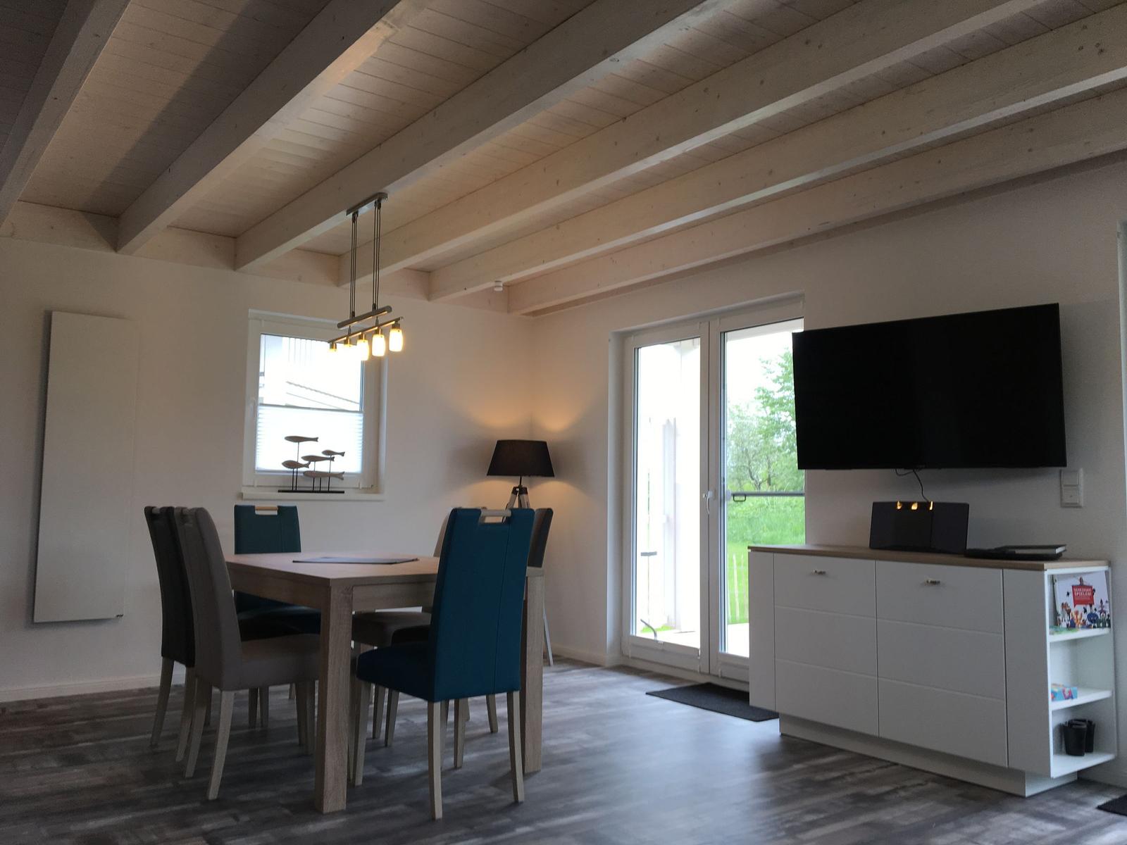 Essbereich mit Tisch und Stühlen, Fernseher und Schlaffenster.
