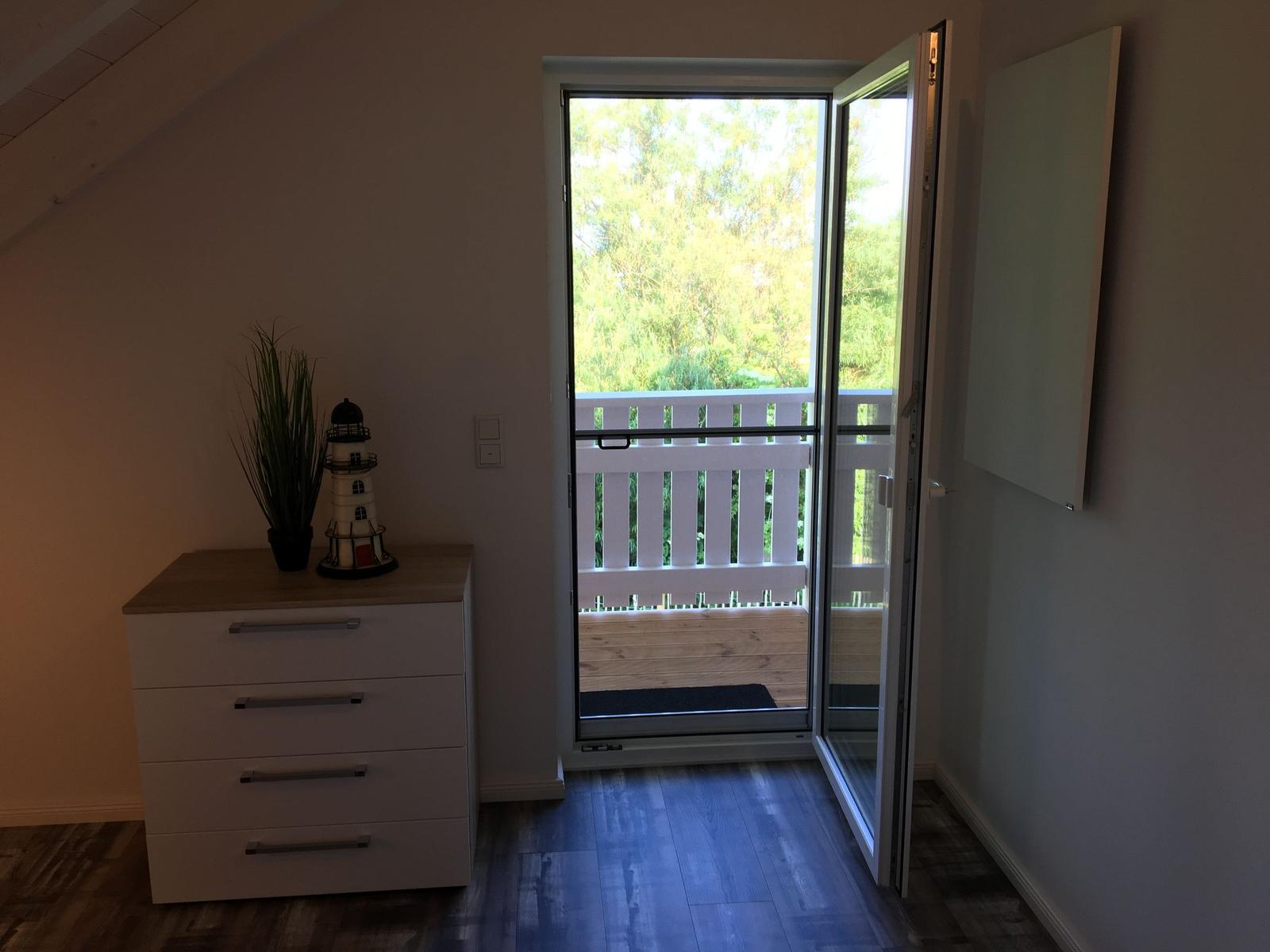 Schlafzimmer mit Balkon, Schrank und Pflanze