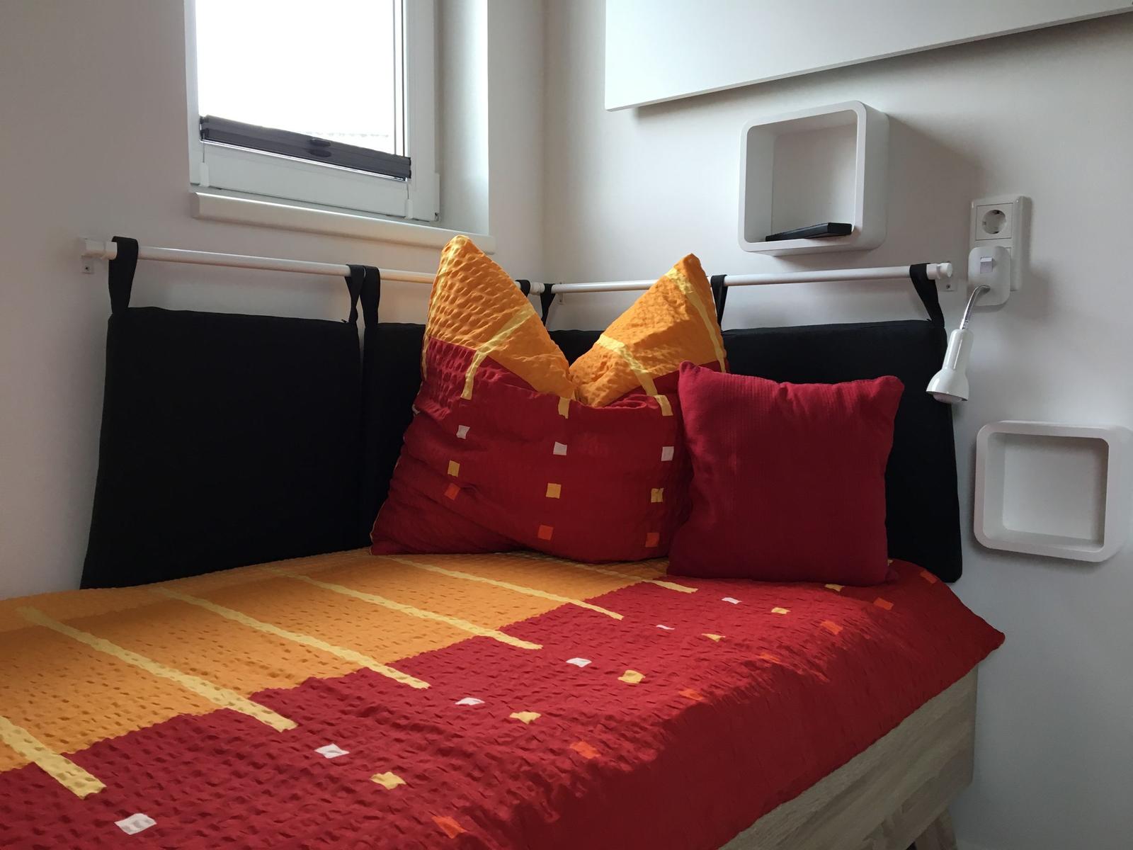 Schlafzimmer mit Bett, Fenster und Wandregal