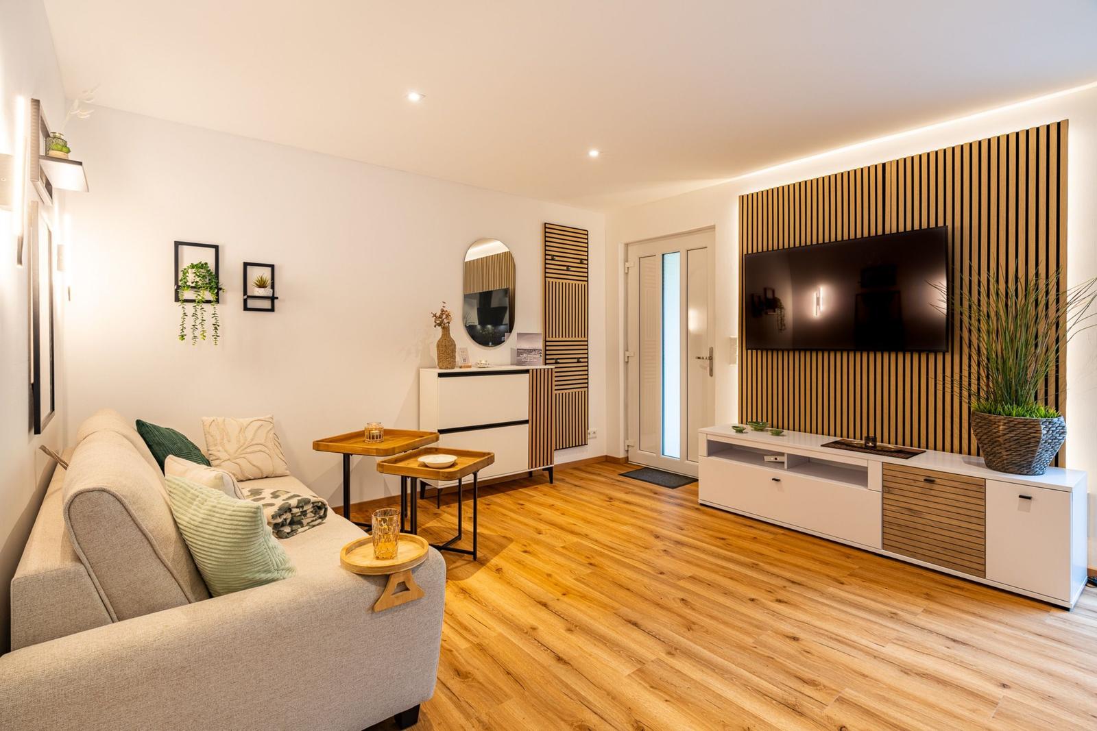 Wohnzimmer mit Sofa, Fernseher und Holzboden.