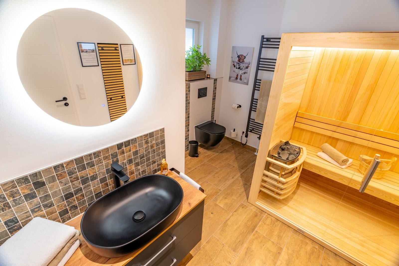 Badezimmer mit Sauna, Waschtisch und Toilette.