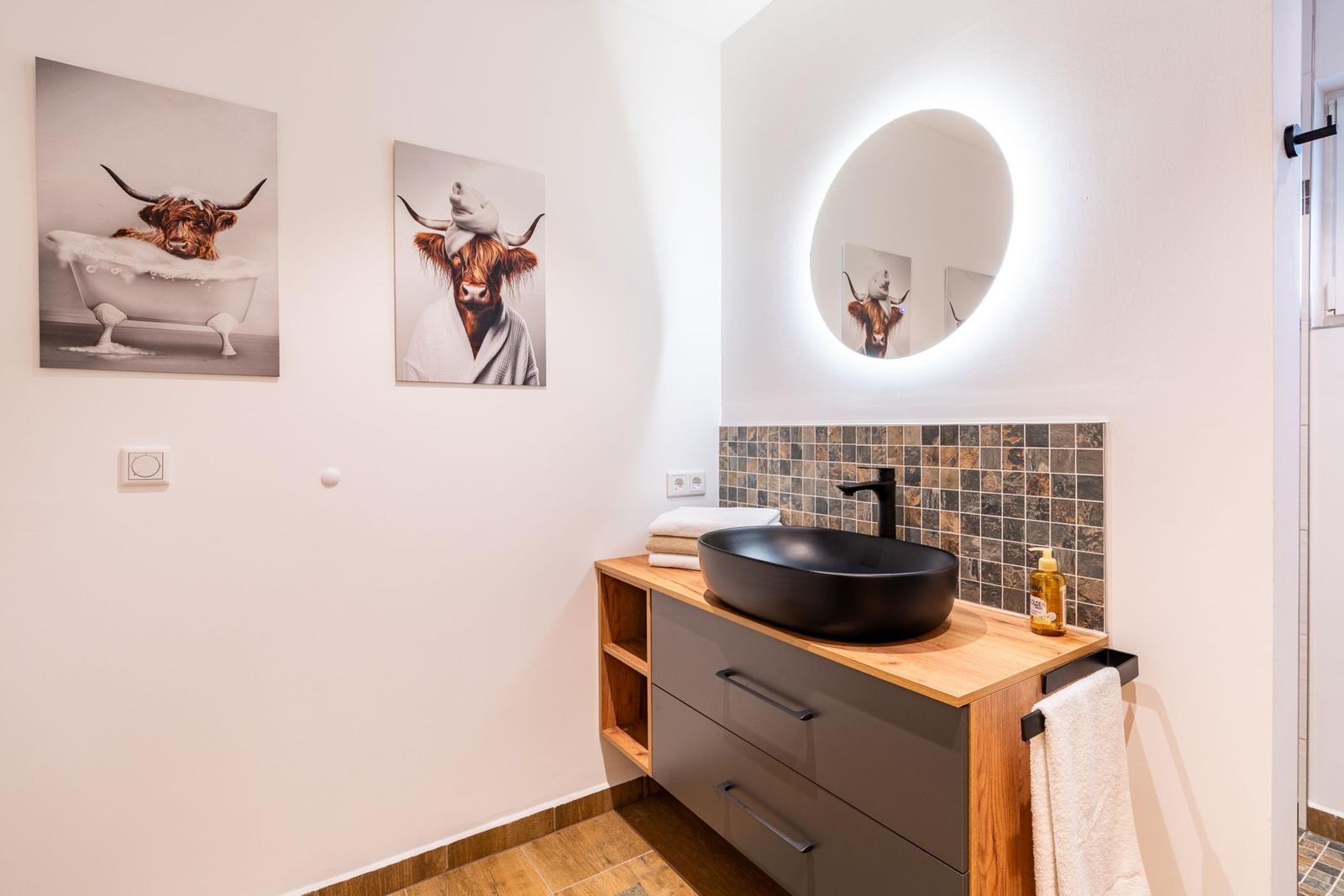 Badezimmer mit Waschtisch, Spiegel und Wandbildern